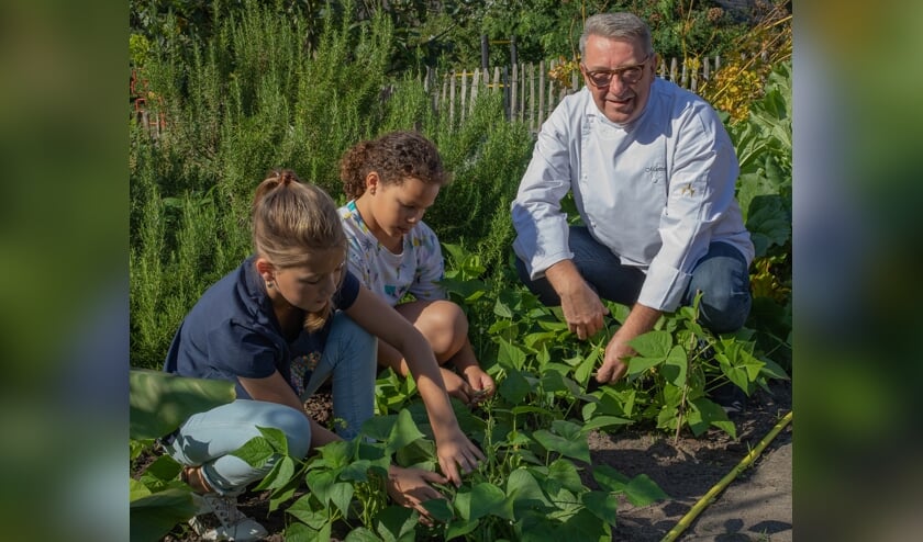 Oprichter Smaakcentrum Martien Bos laat kinderen kennismaken met kruiden en groenten in de Moes- & Beweegtuin.     