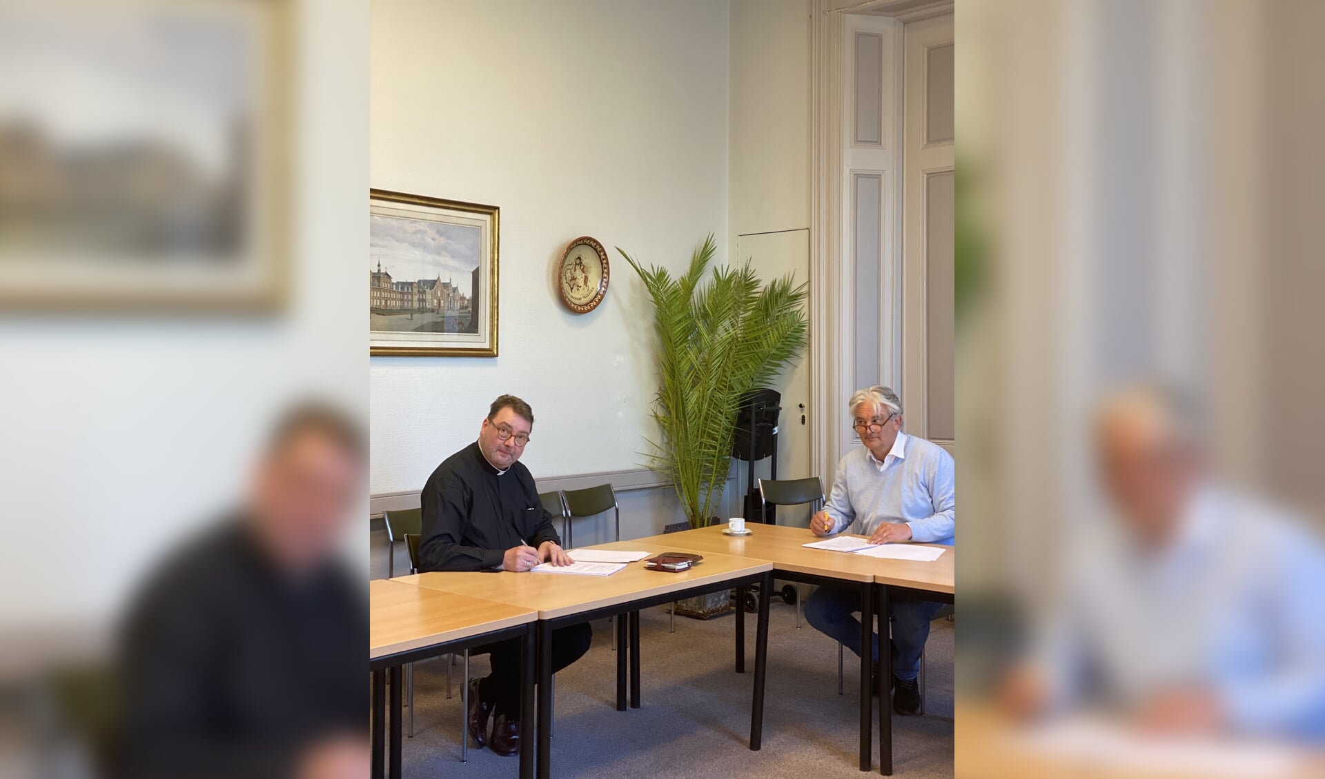 Pastoor Smulders en Ton Verhoeven tekenen de koopovereenkomst. 