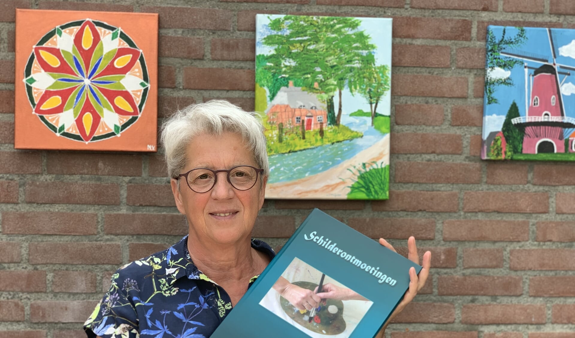 Diny Lamers met haar boek Schilderontmoetingen. 