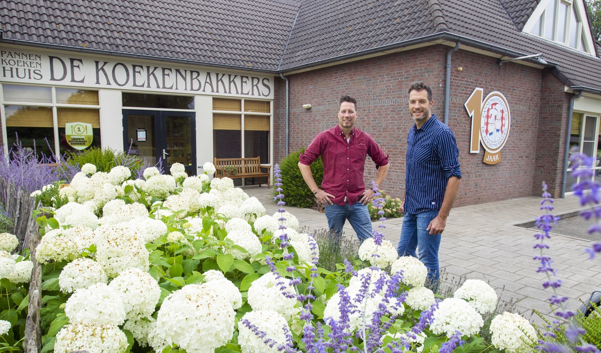 Ondernemers Mark (l) en Bart (r) bij het nieuwe jubileum logo van pannenkoekenhuis De Koekenbakkers (Foto: Ad van de Graaf). 