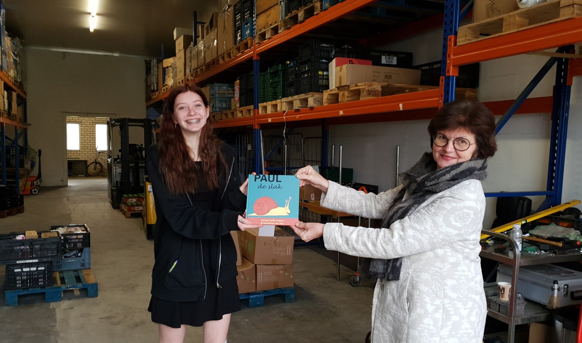 Sira overhandigt het eerste boek aan Régie Driessen van de Voedselbank.