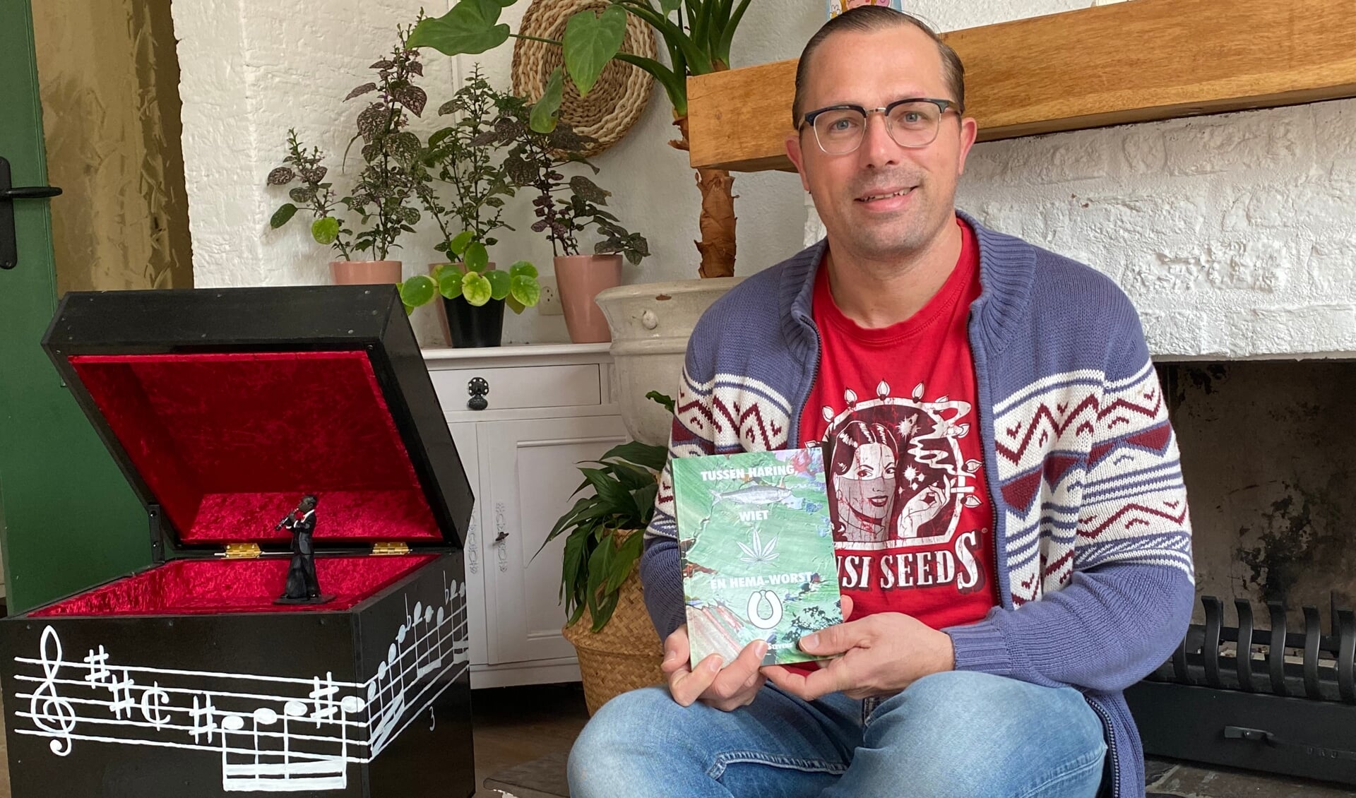 Schrijver Martijn Stevens met zijn nieuwe boek Haring, wiet en Hema-worst bij de openhaard. (Tekst en foto: Jos Gröniger)
