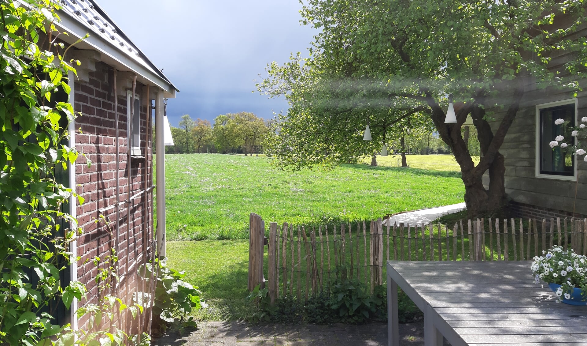 Uitzicht door het raam vanuit het ‘grote’ huis op de mantelzorgwoning die rechts staat met een paadje buitenom naar de deur.