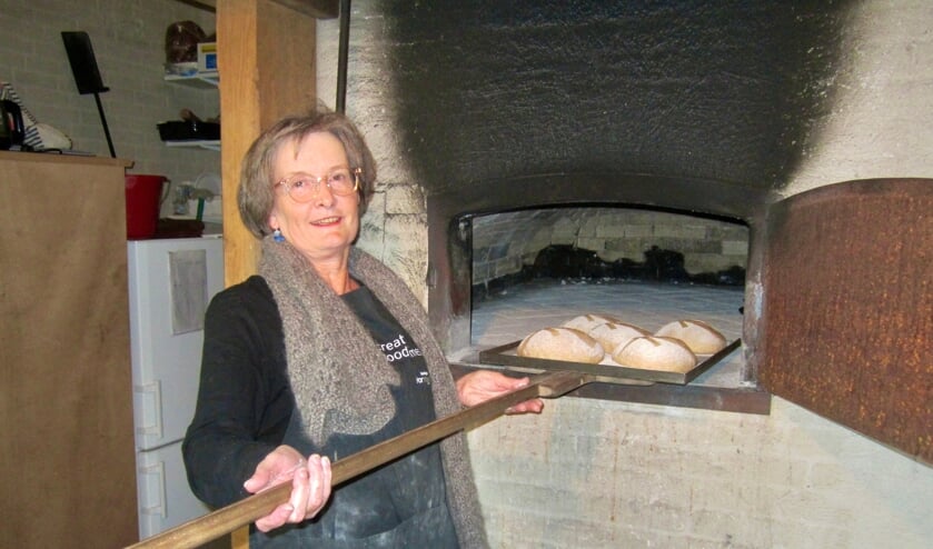 Marianne van den Buuse schuift de broden in de hout gestookte oven.
  