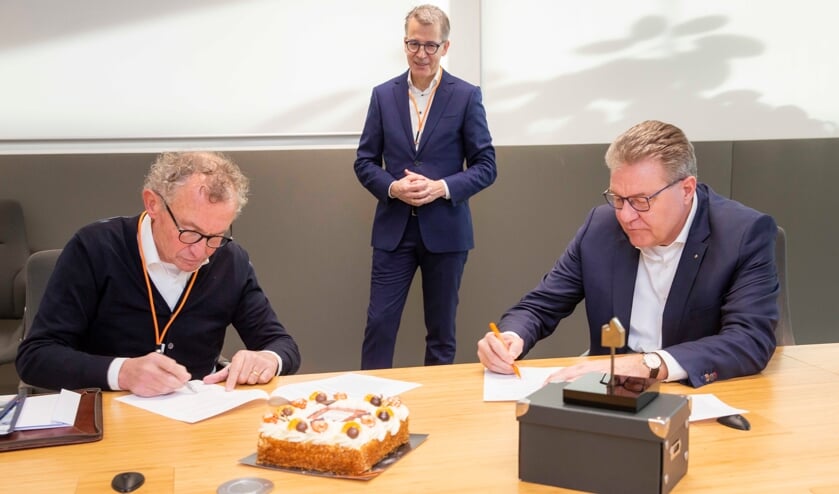 <p>George Jentjens en Herman Molenaar tekenen de contracten, Vermeulen kijkt toe.</p>
