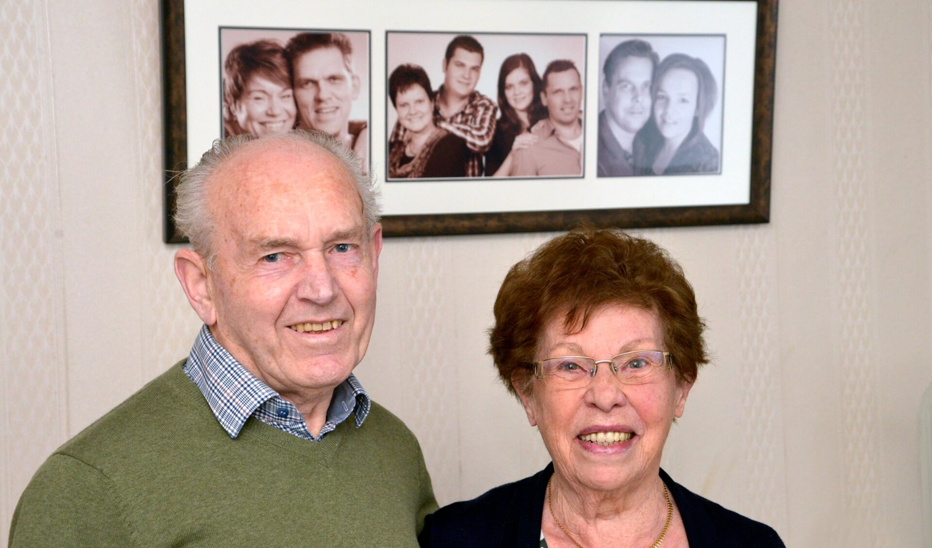 Wim en Riek, met op de achtergrond de foto van hun drie zonen met aanhang.