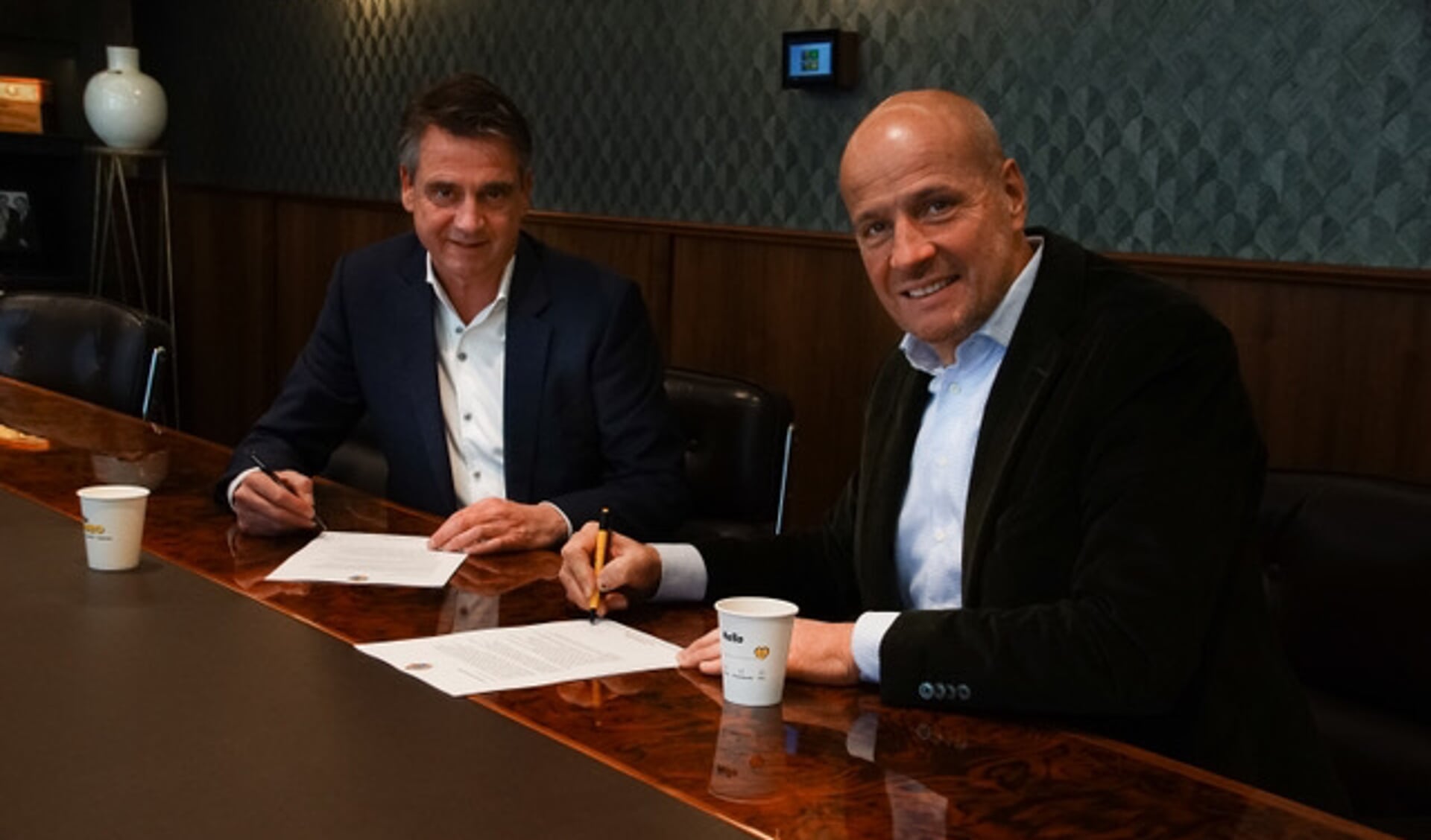 Van den Boom (L) en Van Eerd (R) ondertekenen het contract.