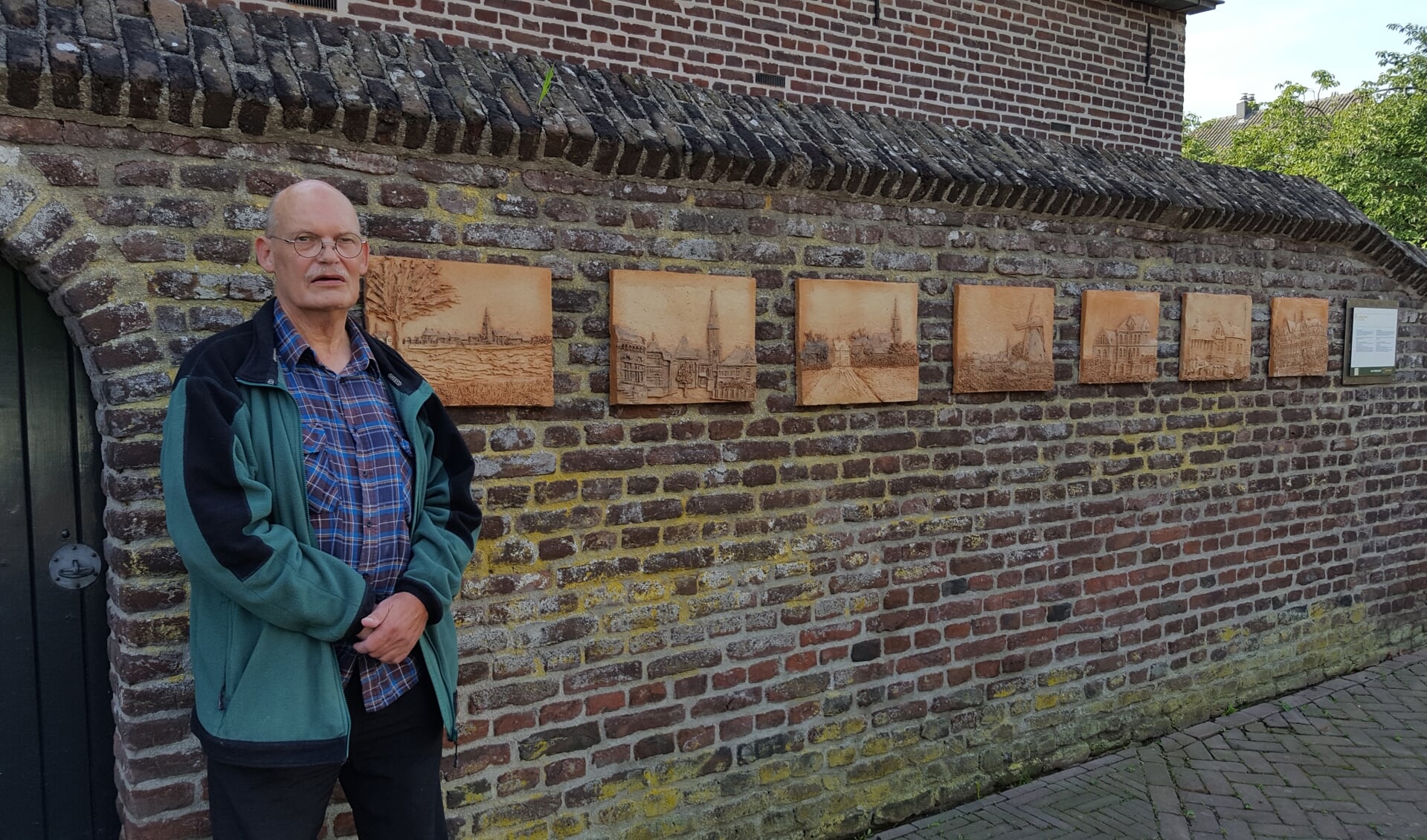 Keramisch activist Pieter Arts bij de aangevulde keramiekmuur op het Raadhuisplein in Ottersum.