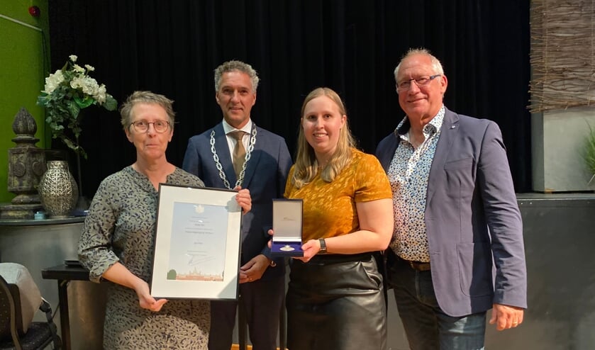 <p>Het trotse bestuur toont de Erepenning en oorkonde. Vanaf links Ilze Elemans, burgemeester Hans Teunissen, Floortje Elemans en Willem Elders.</p>