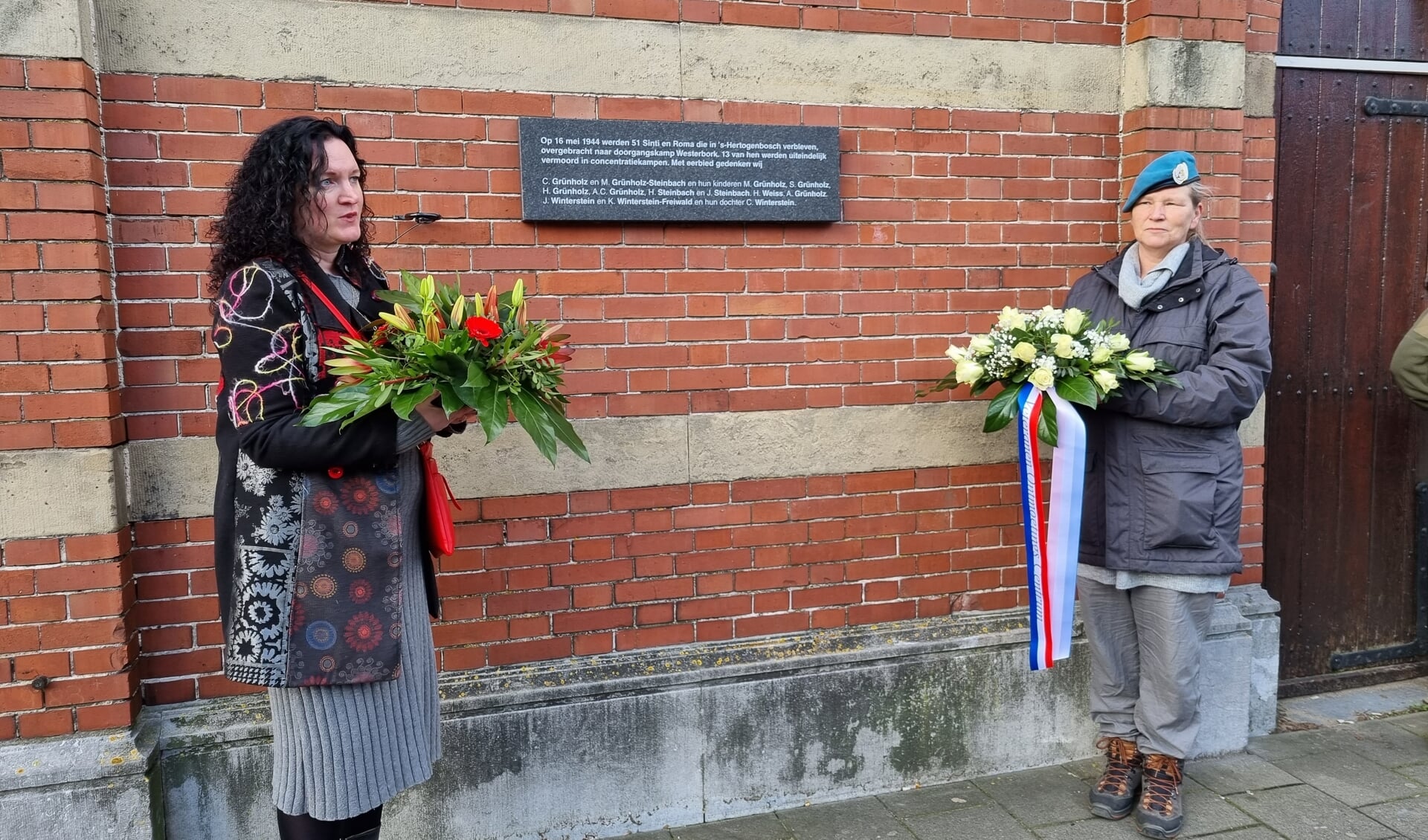 Desirée Coense en Anja van Zetten leggen een krans bij de plaquette ter nagedachtenis aan de razzia op 16 mei 1944. (Foto: Henk van Esch)