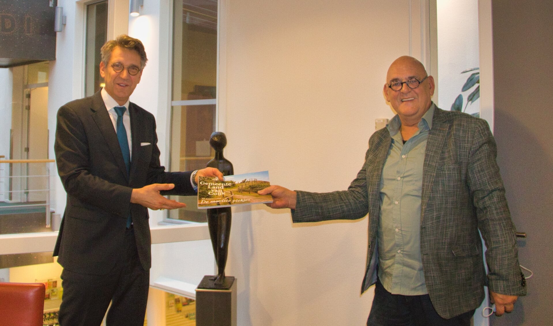 Jan Hendriks (rechts) overhandigde het boek 'De gemeente Land van Cuijk. De mooiste plekjes' aan burgemeester Wim Hillenaar.