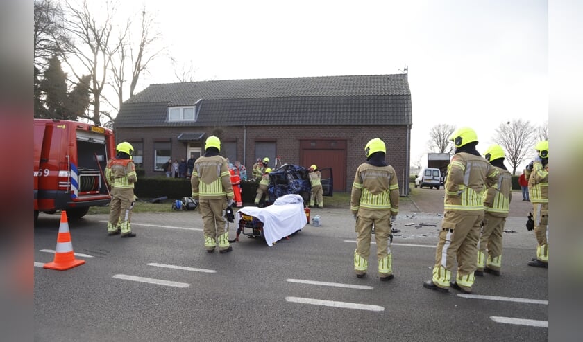 Hulpverleners bevrijden een inzittende uit het personenvoertuig.