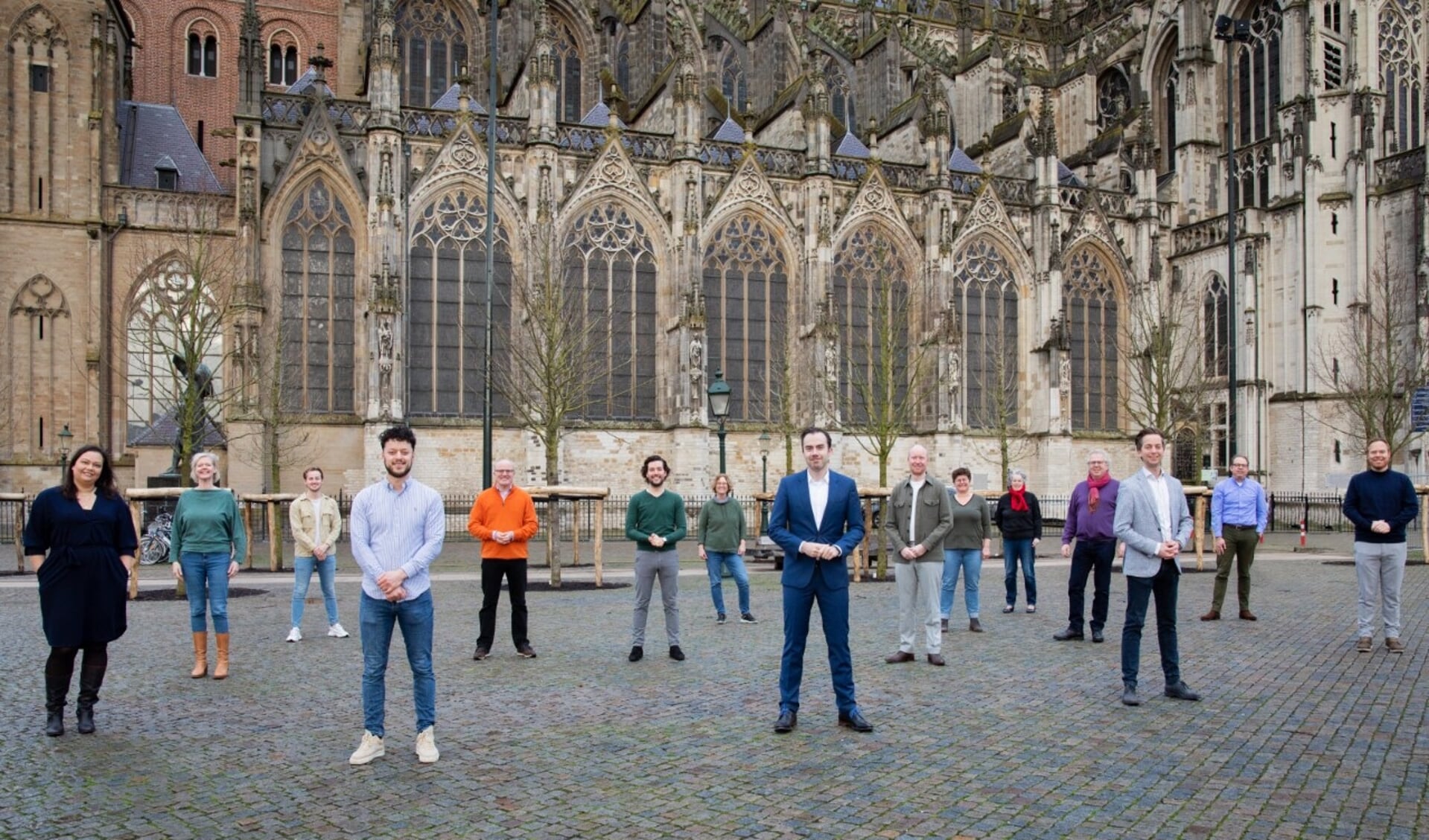 Een groot deel van de kandidaten die namens D66-'s-Hertogenbosch deelnemen aan de komende gemeenteraadsverkiezingen poseren samen op het grote plein voor de Sint-Janskathedraal.