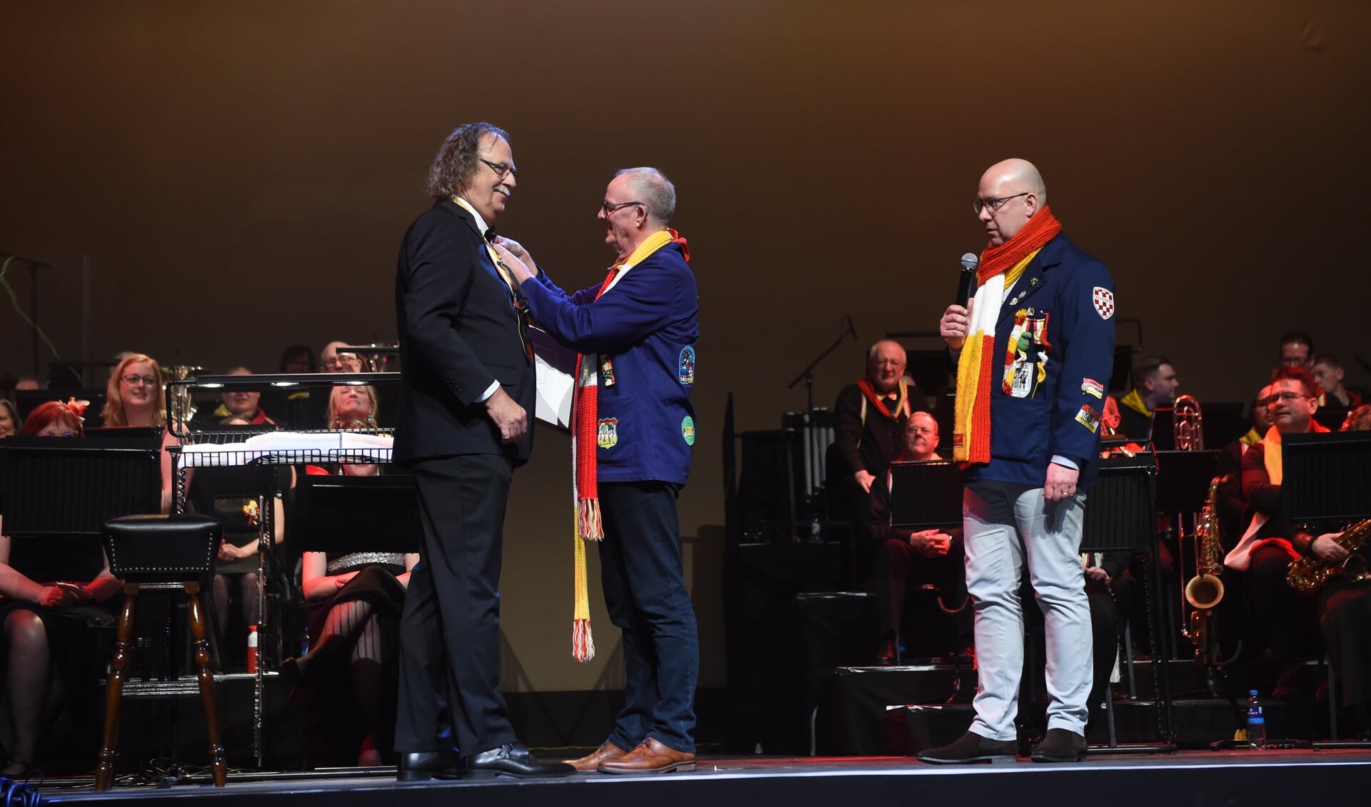 De voorzitter van de Koninklijke Harmonie Harry van der Krabben speldt dirigent Sjef Ipskamp de onderscheiding op.