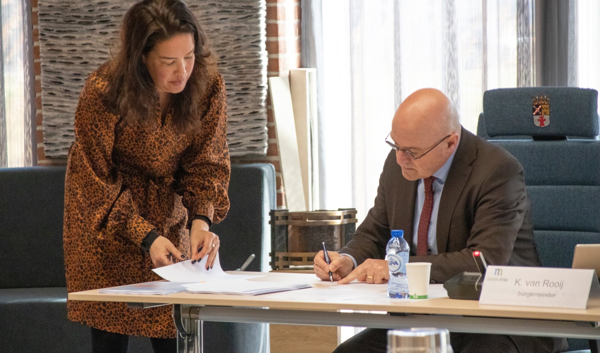 Burgemeester Kees van Rooij (R) tekent het proces-verbaal. Mijke Soejoko, projectleider verkiezingen, kijkt toe.