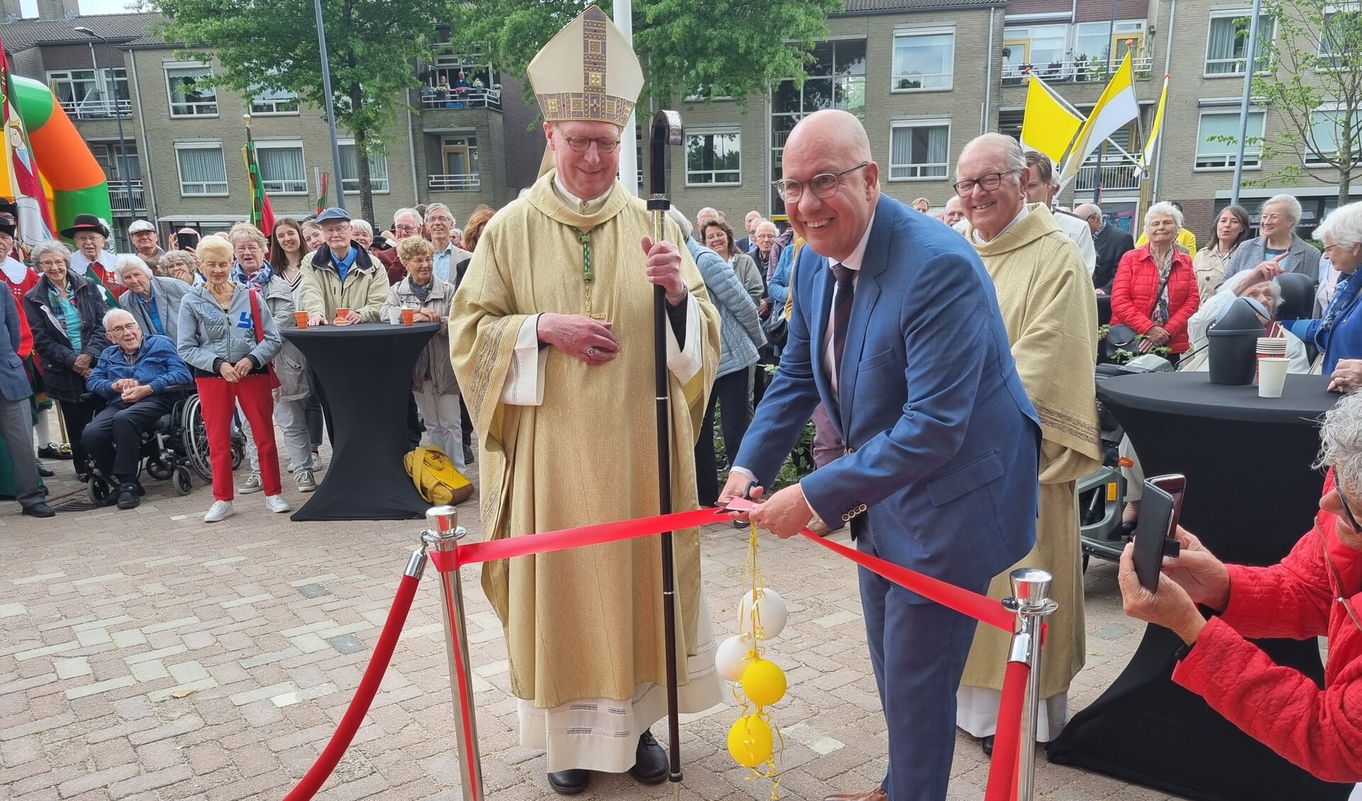 Burgemeester Jack Mikkers knipt onder toeziend oog van bisschop Gerard de Korte het lint door van het parochiecentrum.