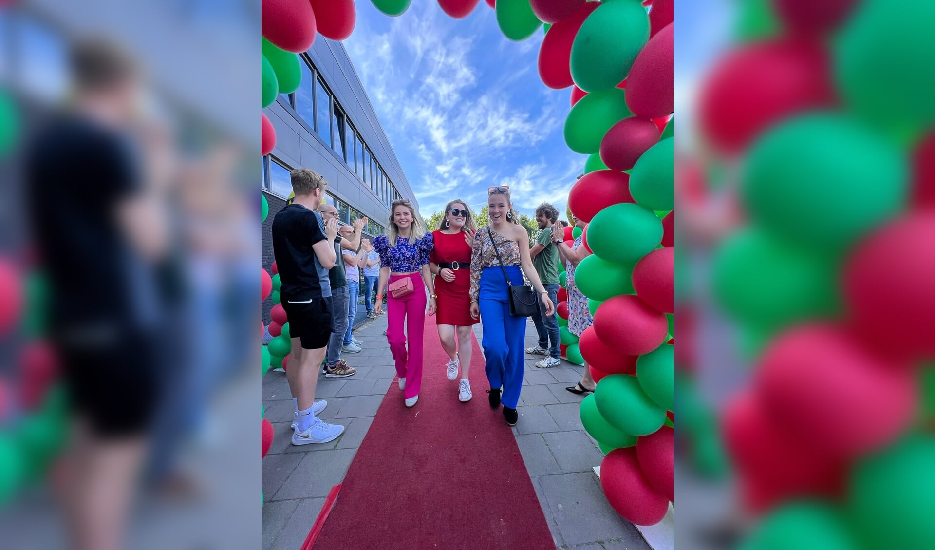 Geslaagden over de rode loper onder luid applaus van docenten en door een boog met rode/groene ballonnen op Metameer jenaplan Boxmeer. 