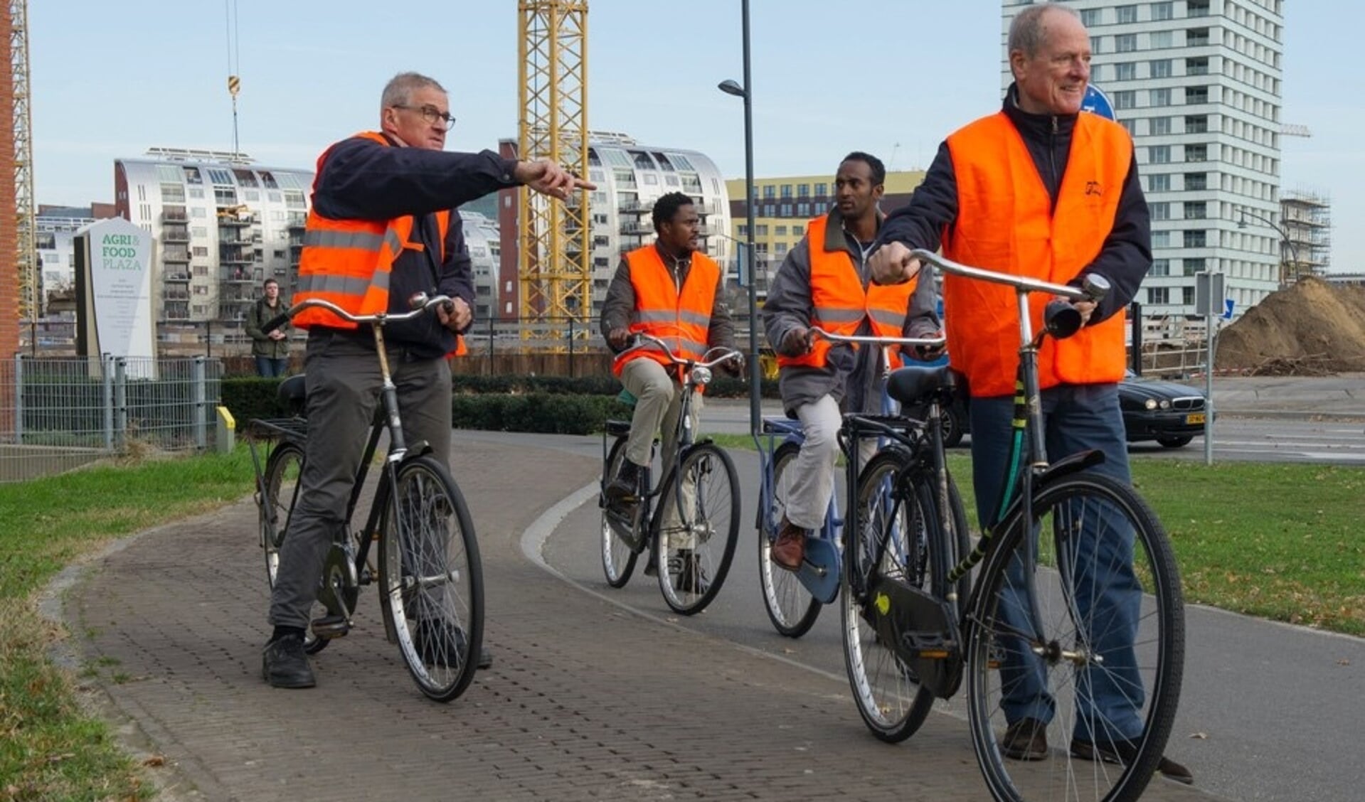Willem van Engelen (links) legt een verkeerssituatie uit aan twee Eritrese vluchtelingen die voor het eerst op de fiets de stad in gaan.
