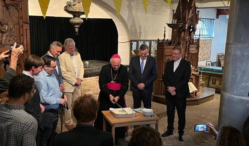 Hulpbisschop De Jong snijdt bij de opening van het Dialoloogmuseum de Limburgse vlaai aan met het zwaard van Sint Martinus.  