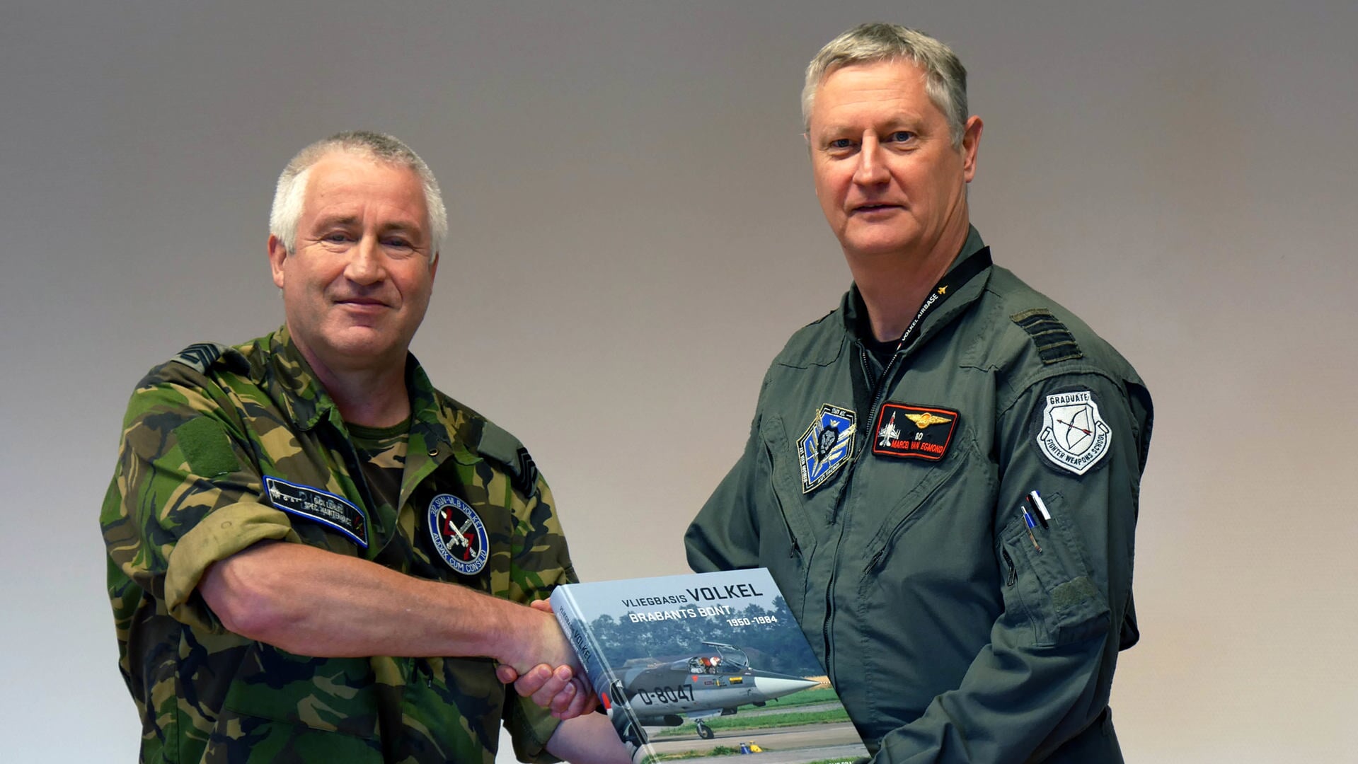 Dick Lohuis (l) overhandigt een exemplaar van het boek aan commandant Marcel van Egmond.