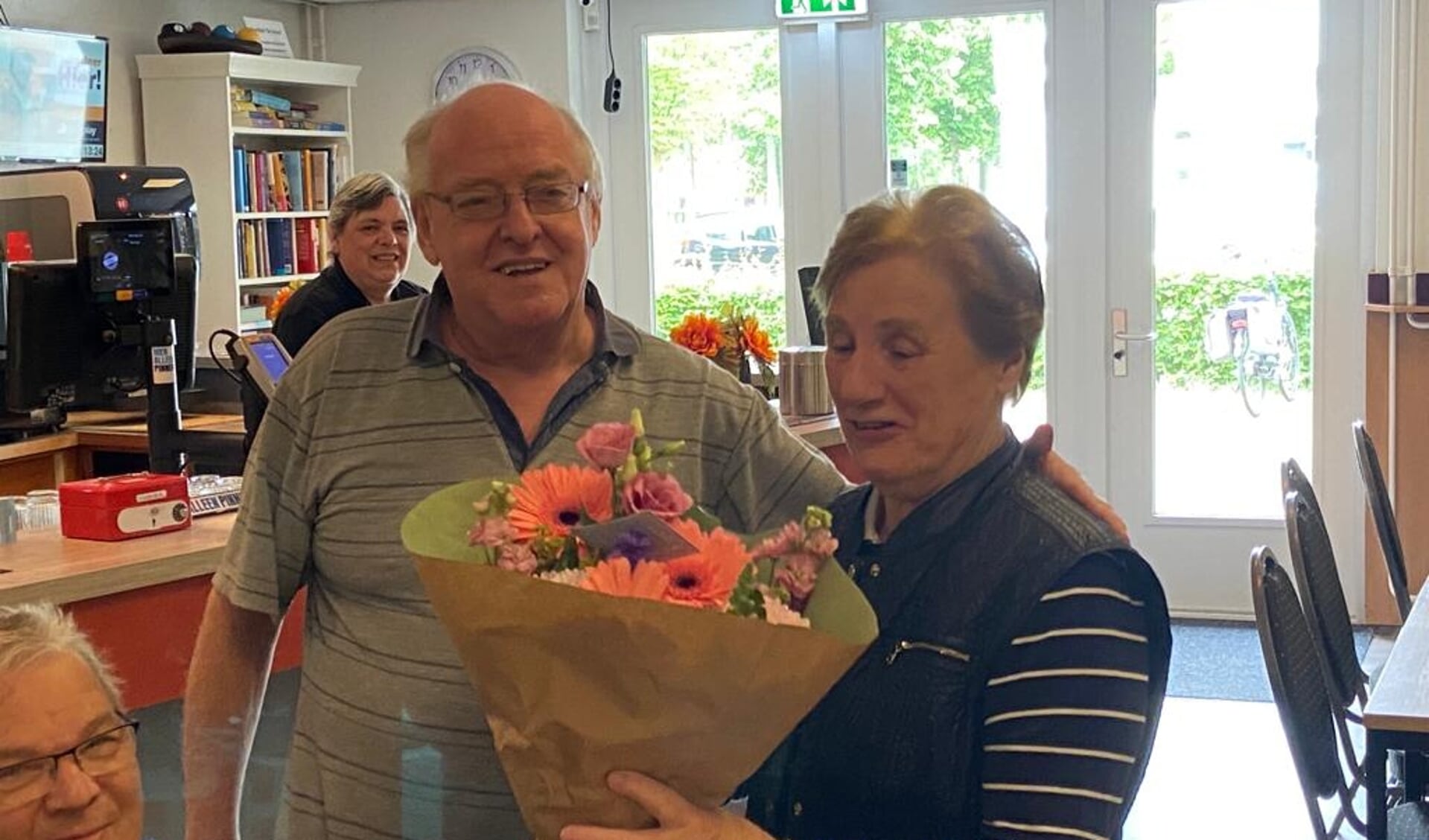 Voorzitter Tonny van Eenbergen overhandigt de bloemen aan mevrouw Van Langen. Zij is het honderdste lid van de seniorenvereniging. 
