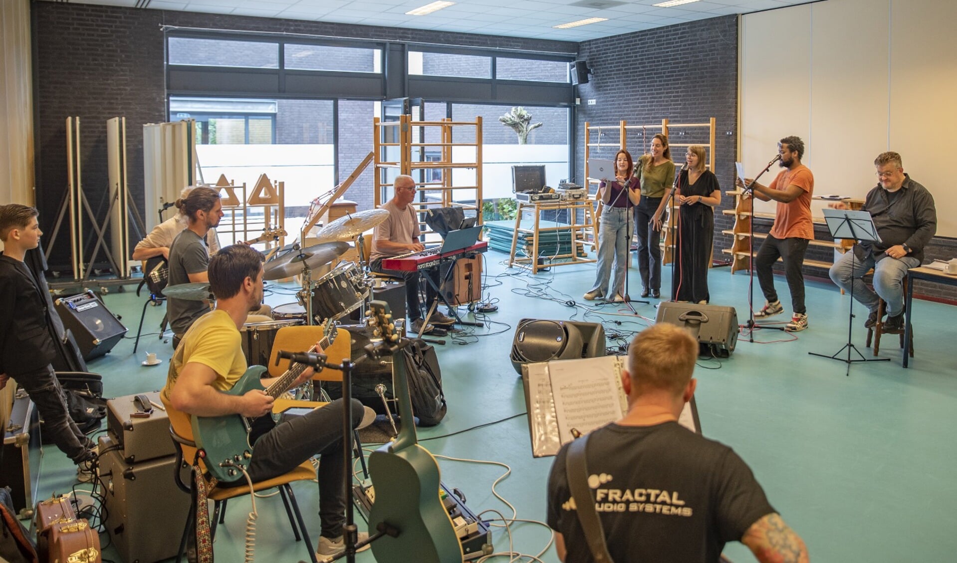 Zanger Emceeyn, begeleid door drie zangeressen en het combo, tijdens een van de repetities van ‘De Vrienden van Oelbroeck Live’. Rechts dirigent Marc Thijssen. Foto: SPG Photos.