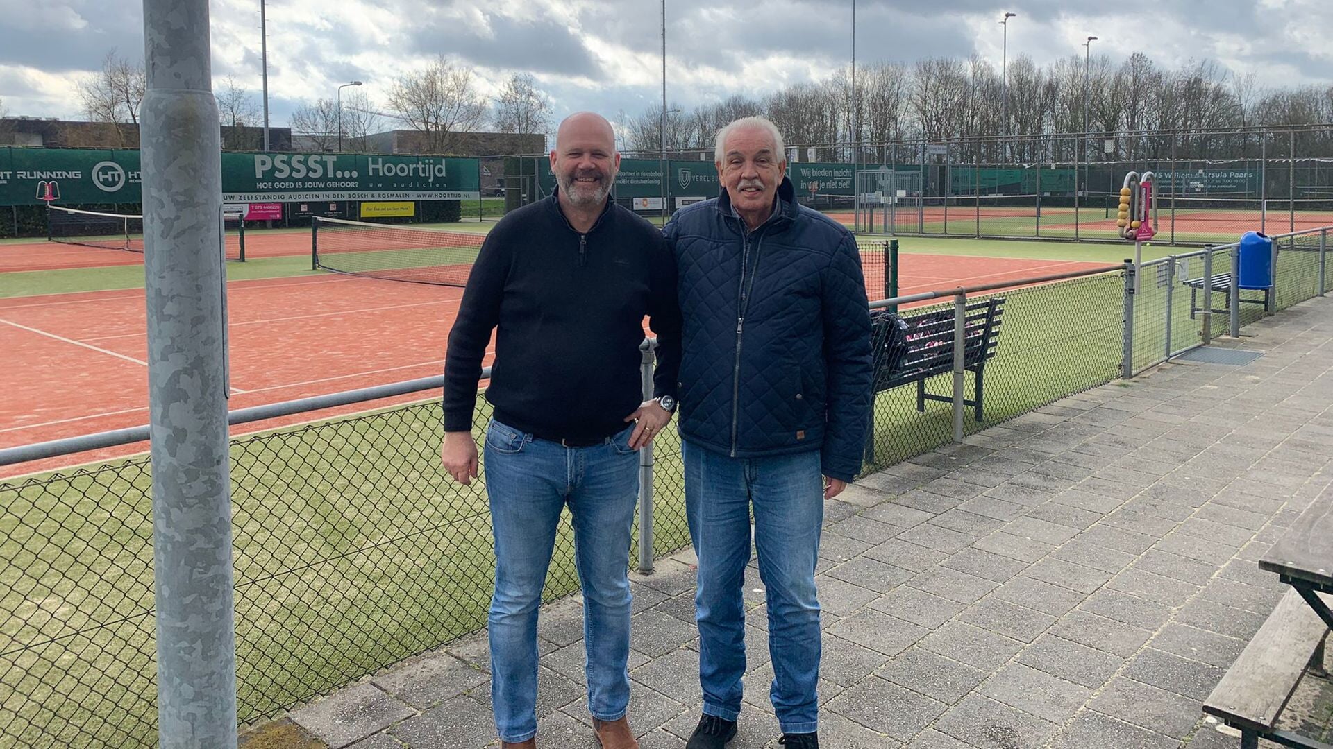 De nieuwe voorzitter Dennis Hielkema (links) en de vertrekkende voorzitter Cor Schrauwen (rechts) poseren gezamenlijk voor één van de tien tennisvelden van hun geliefde tennisvereniging. 