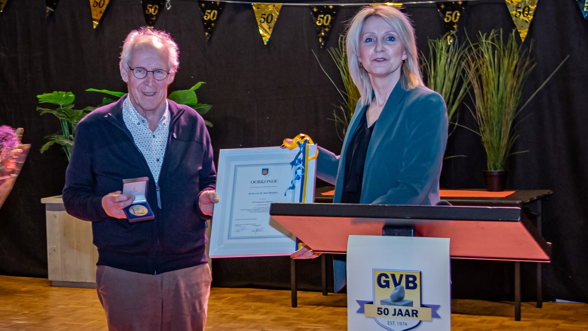Burgemeester Caroline van den Elsen reikt de penning van verdienste uit aan Jan Manders.