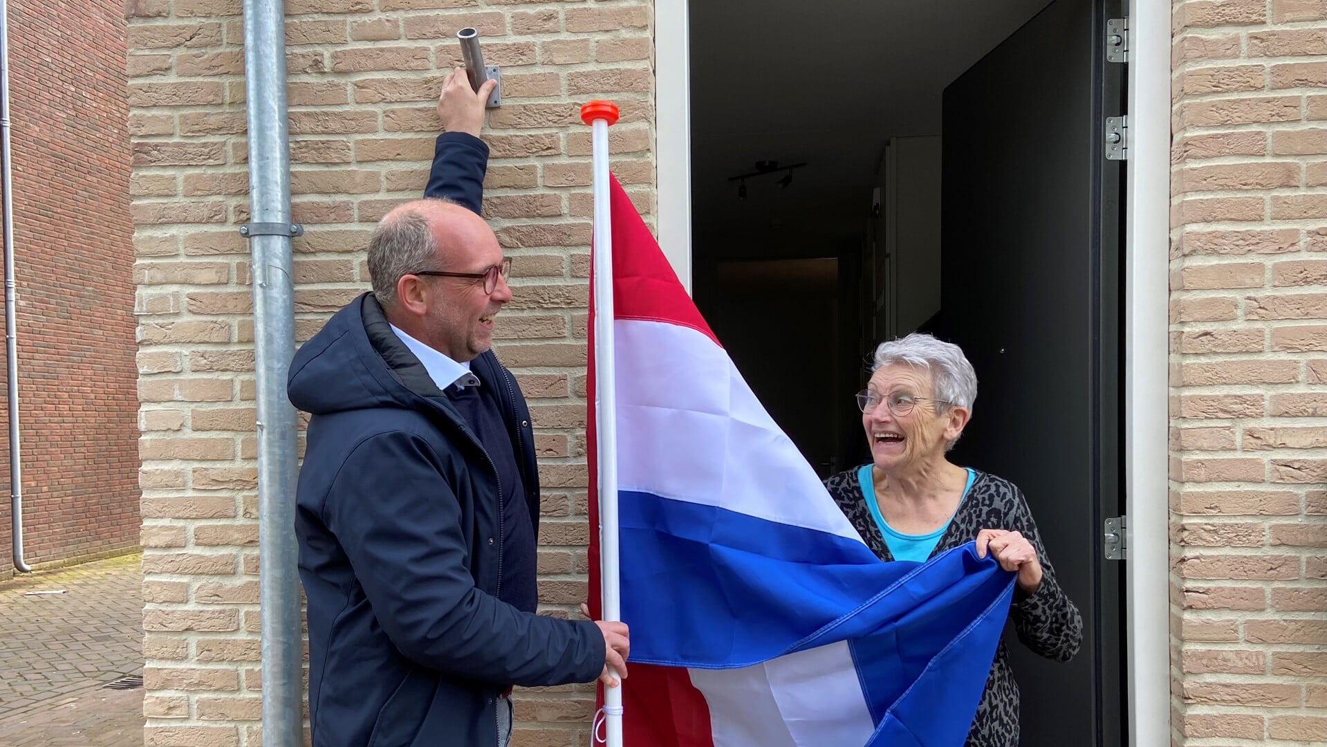 Dirk Lammers overhandigt mevrouw Ketelaars uit de Hoogstraat een Nederlandse vlag.