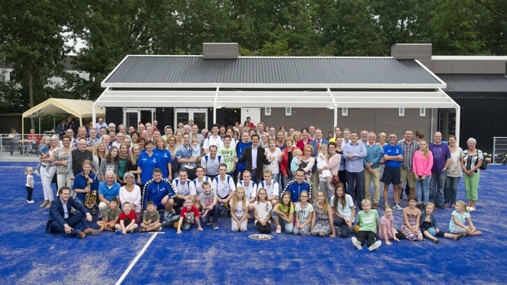 Groepsfoto met alle leden van Handbalvereniging Blauw-Wit met op de achtergrond het huidige clubhuis aan Het Wielsem in Den Bosch. 