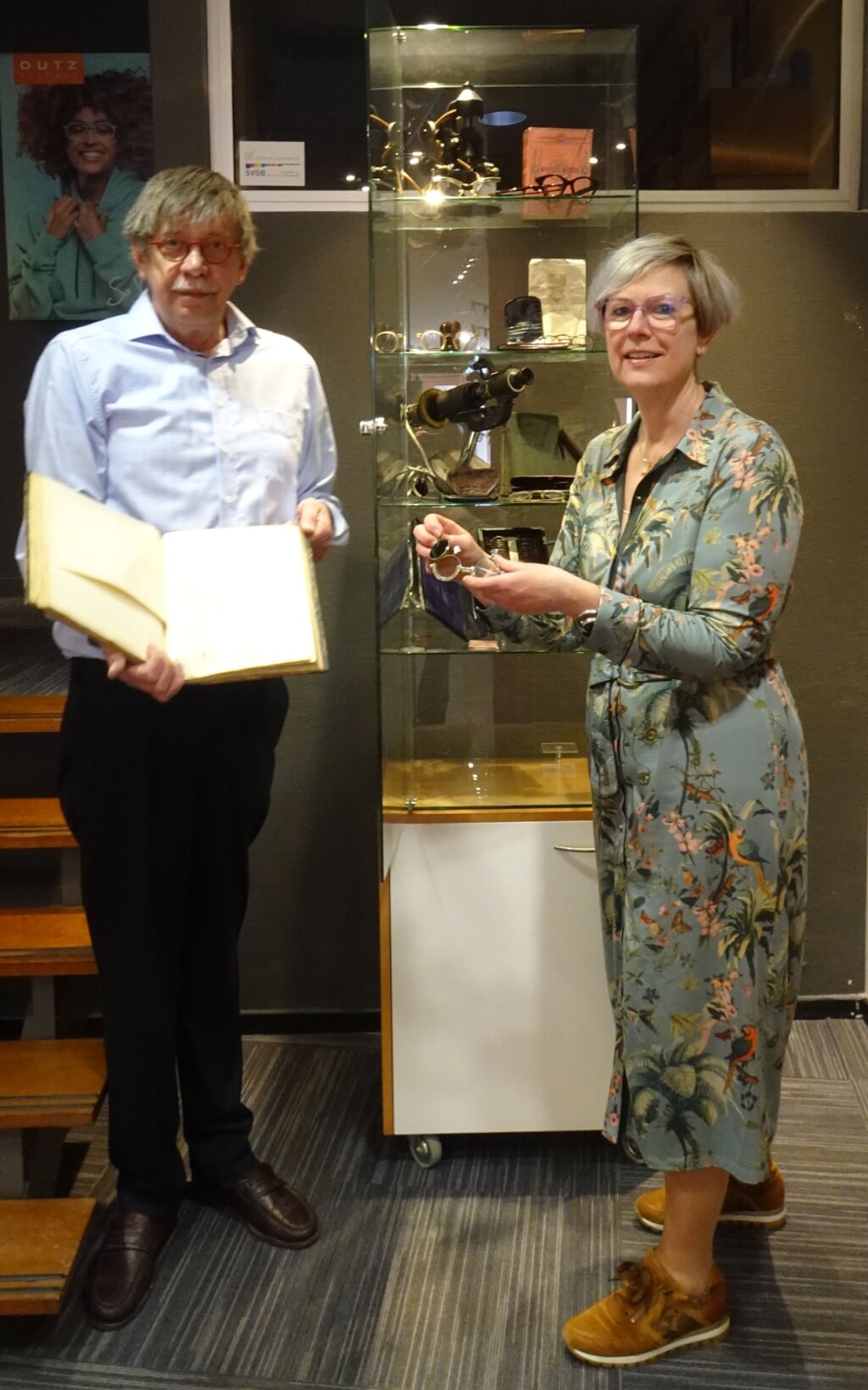 Theo van Hout en Lianne van Asperdt geven vitrine met antieke optiek apparatuur aan SIEMei. 