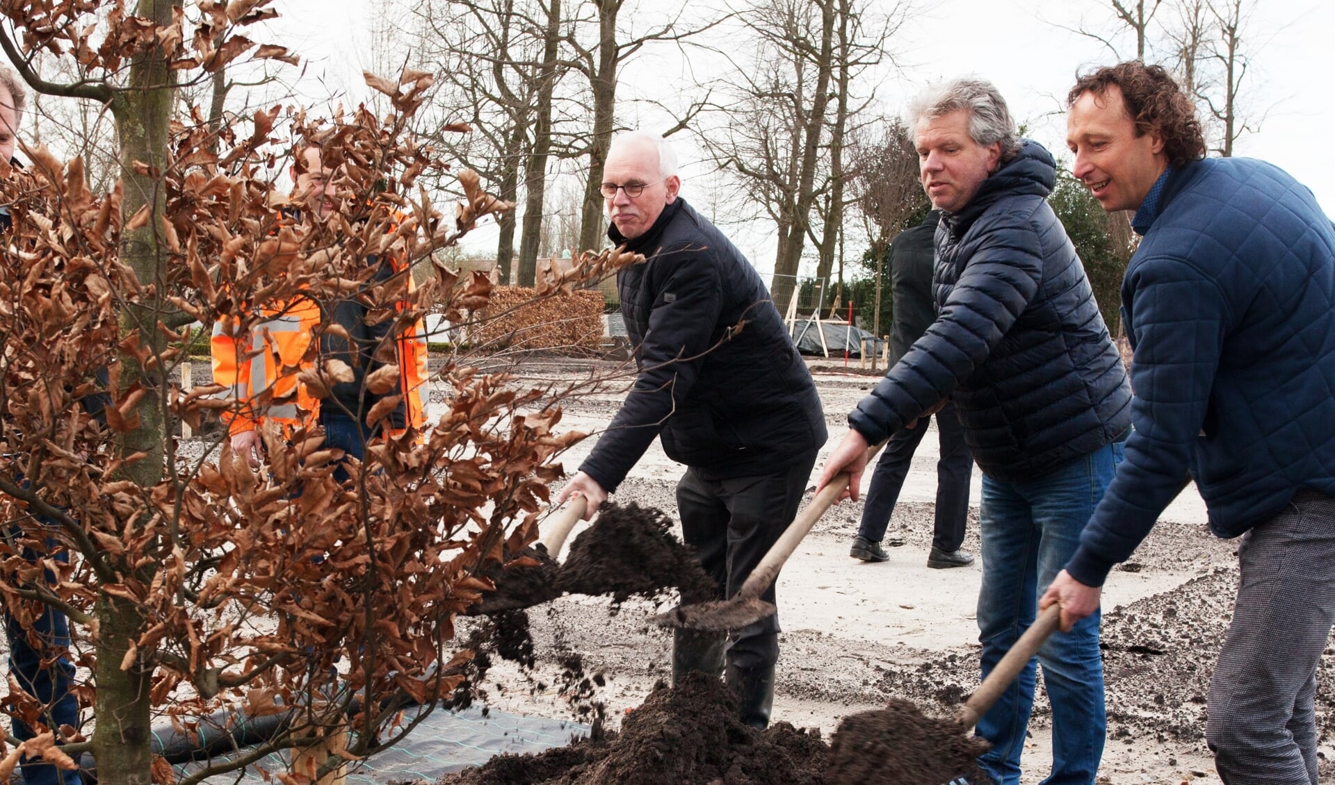Wethouder Kees Oskam plant, samen met de veretgenwoordigers van de vroegere grondeigenaren Ard Op 't Landt (rechts) en Kees Bakker, de eerste boom