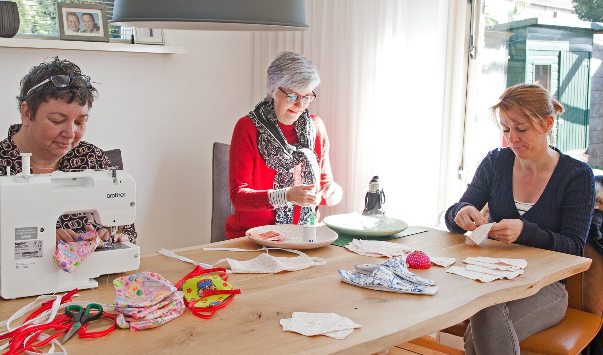 Marjolein Kranenburg (links), Inge Wisselink en Wilma Neven druk aan het werk aan de mondkapjes.