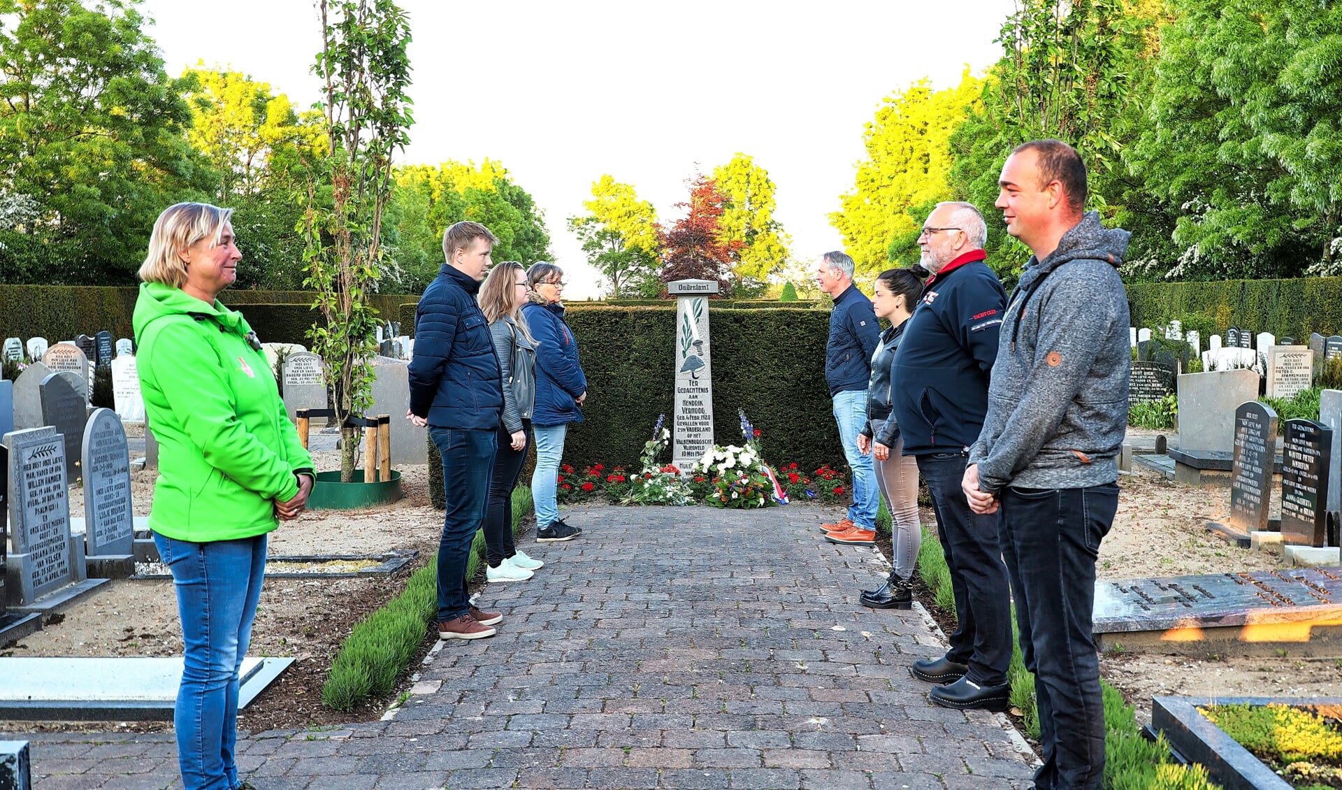 Het bestuur van de Oranjevereniging in Waarder op gepaste afstand bij het monument voor Hendrik Verhoog op de begraafplaats in Waarder