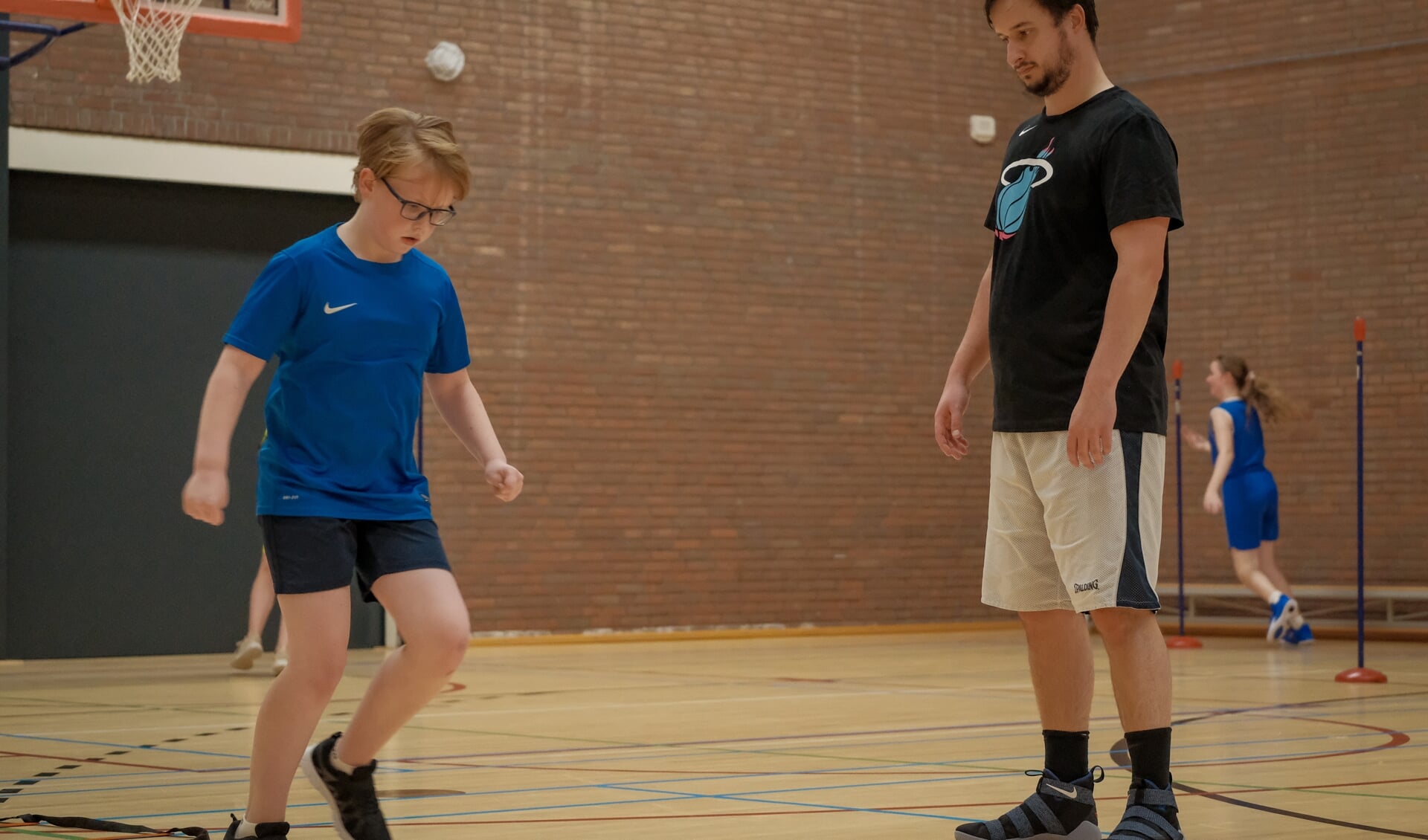 Vrijwilliger Alexander van den Heuvel geeft instructie aan een jeugdlid van Basketbalvereniging Popeye.