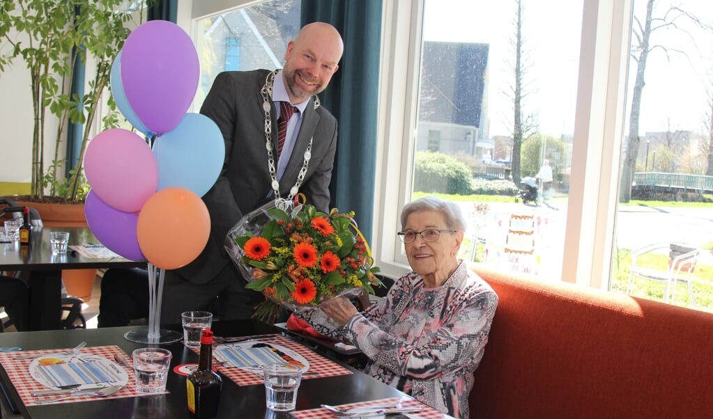 Felicitaties en een bloemetje voor de 100 jarige mevrouw Huizer Martins namens de gemeente uit handen van burgemeester Michiel Grauss. Beeld:  Marlien van Leeuwen