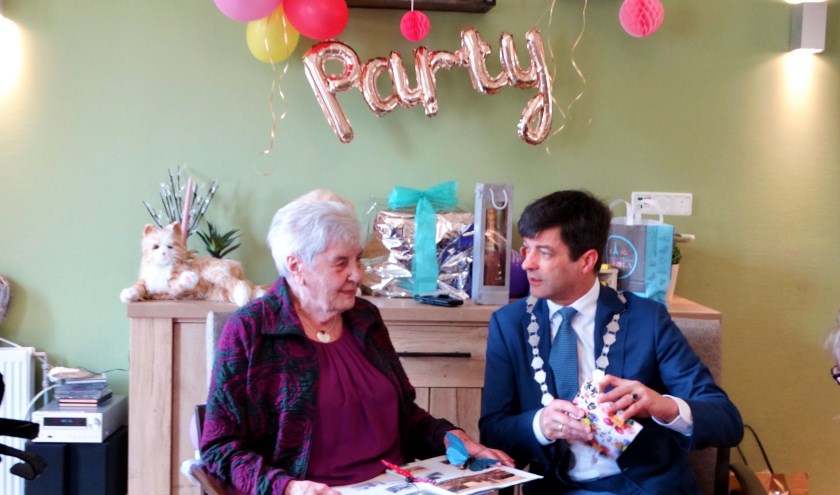 Neeltje van Gemeren-Kruithof pakt samen met de burgemeester haar cadeautjes uit.