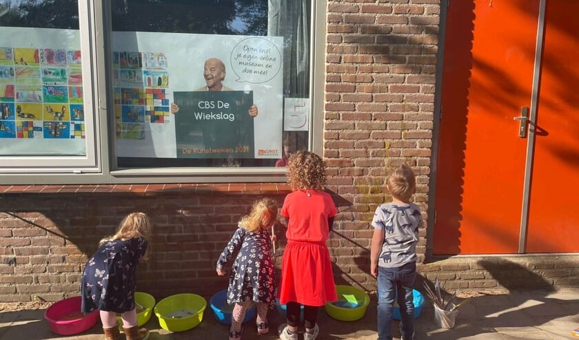 <p>Kleuters verven hun mooie kunstwerk op de muur van de school.</p>