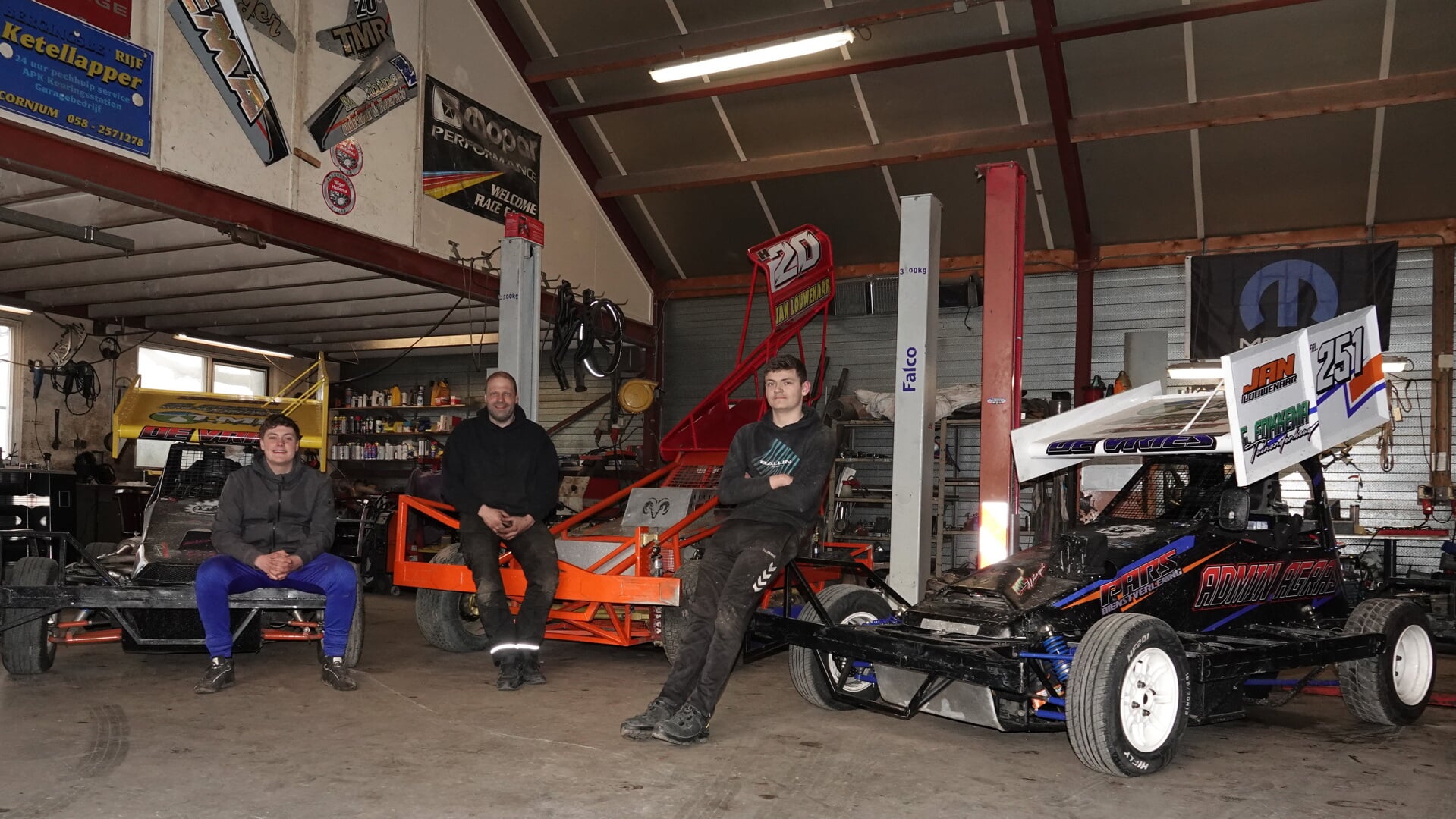 Jorn, Bert en Rick de Vries poseren in de werkplaats bij hun Stockcars 