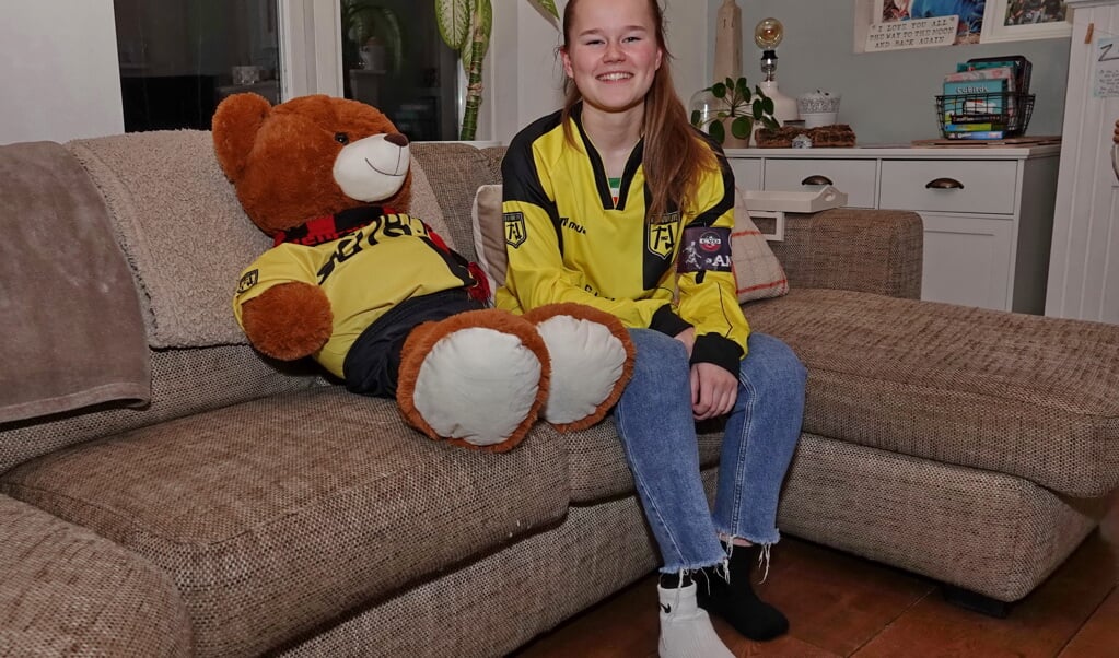 Samen met haar cadeau gekregen knuffelbeer zit Anna thuis op de bank, allebei in Ouwe-Syl shirt, de beer met CVO sjaal