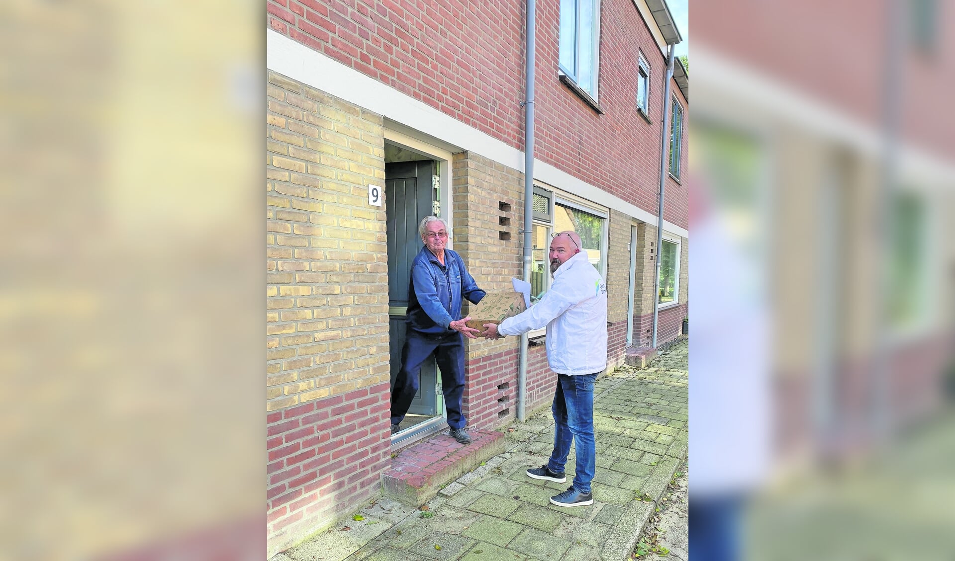 Wim Jansen bewoner van de Reigerstraat krijgt het bedankpakketje uitgereikt.