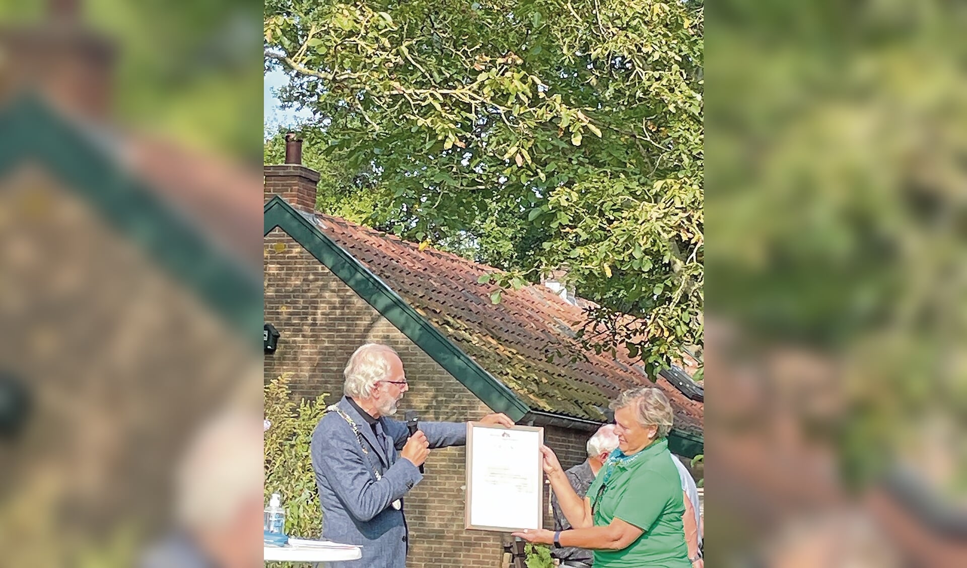 Burgemeester Molkenboer van Woerden overhandigt de oorkonde aan José van Engelen, de voorzitster van de werkgroep De Kievit.