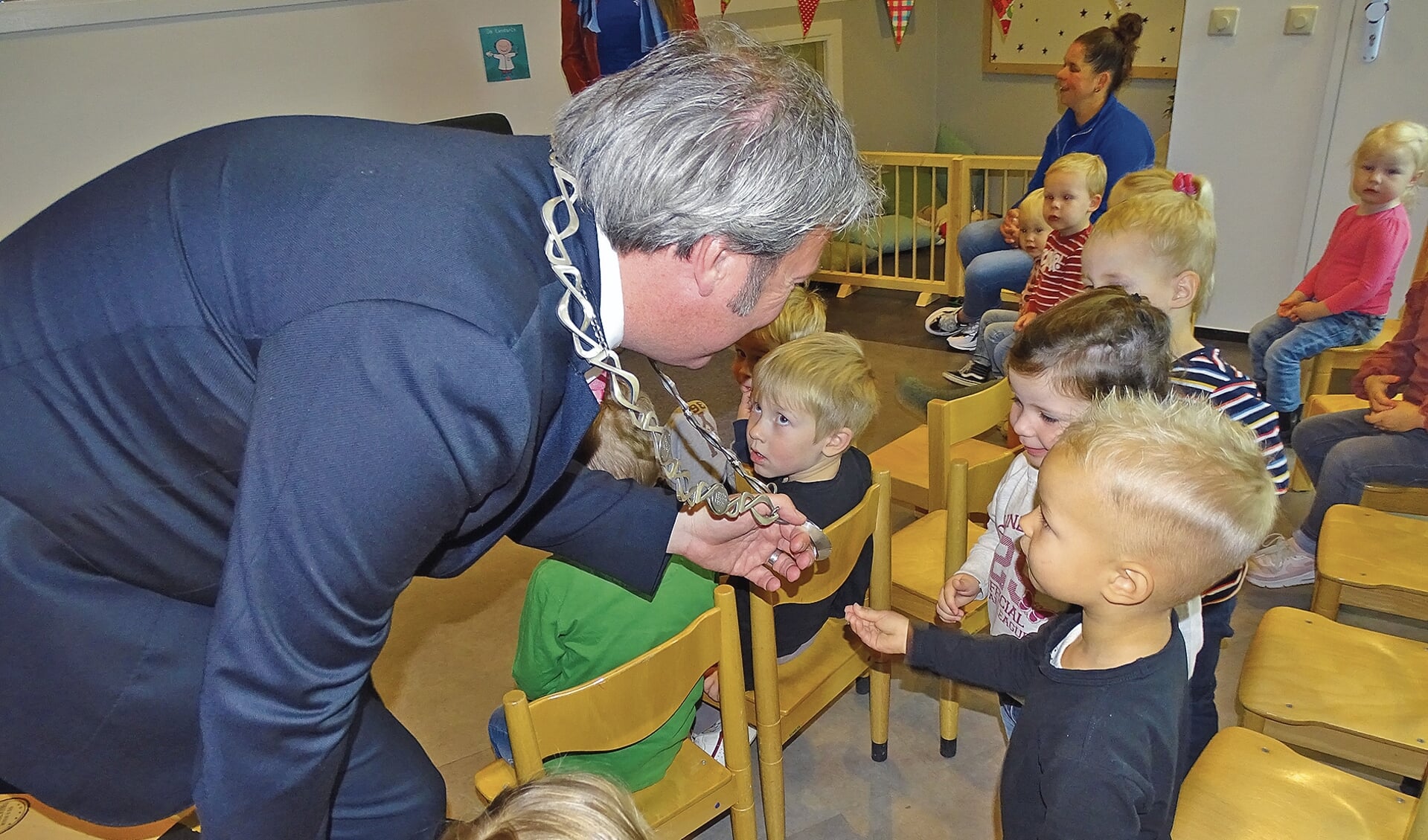 De burgemeester laat eerst zijn ambtsketting voelen aan de kinderen voordat hij voor gaat lezen.