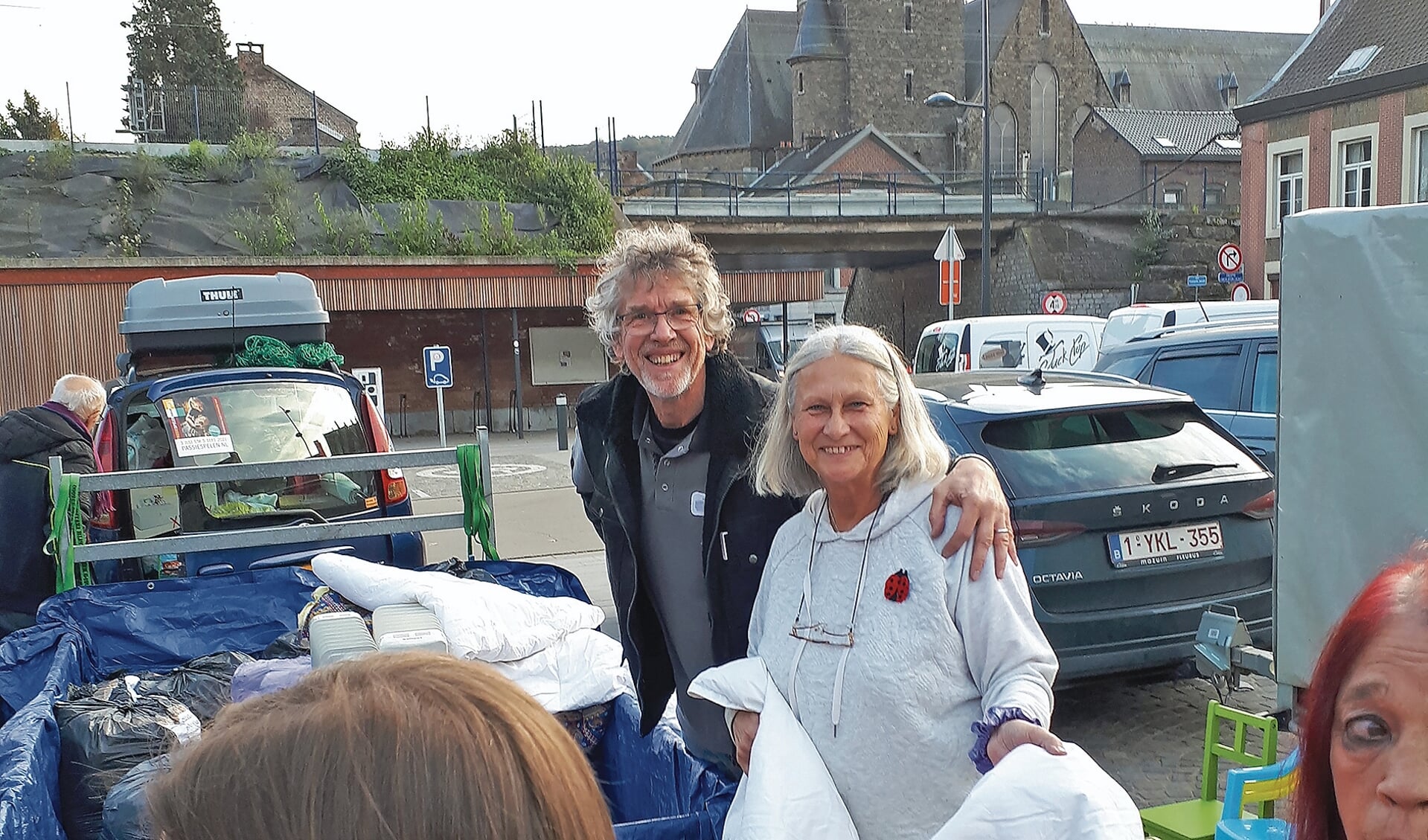 Anita Peeters en Jaap Gerssen staan op een parkeerplaats kleding uit te delen.