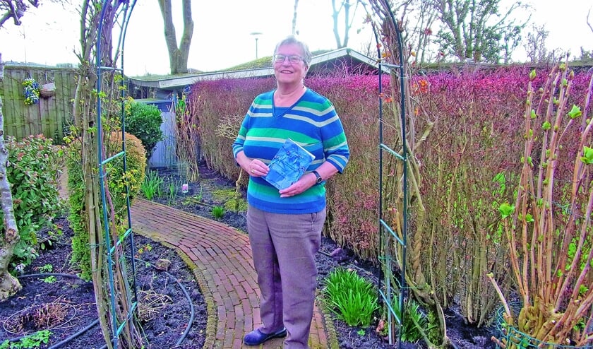 <p pstyle="BODY">Nettie Kuijer poseert met haar boek in de rozenboog.</p>