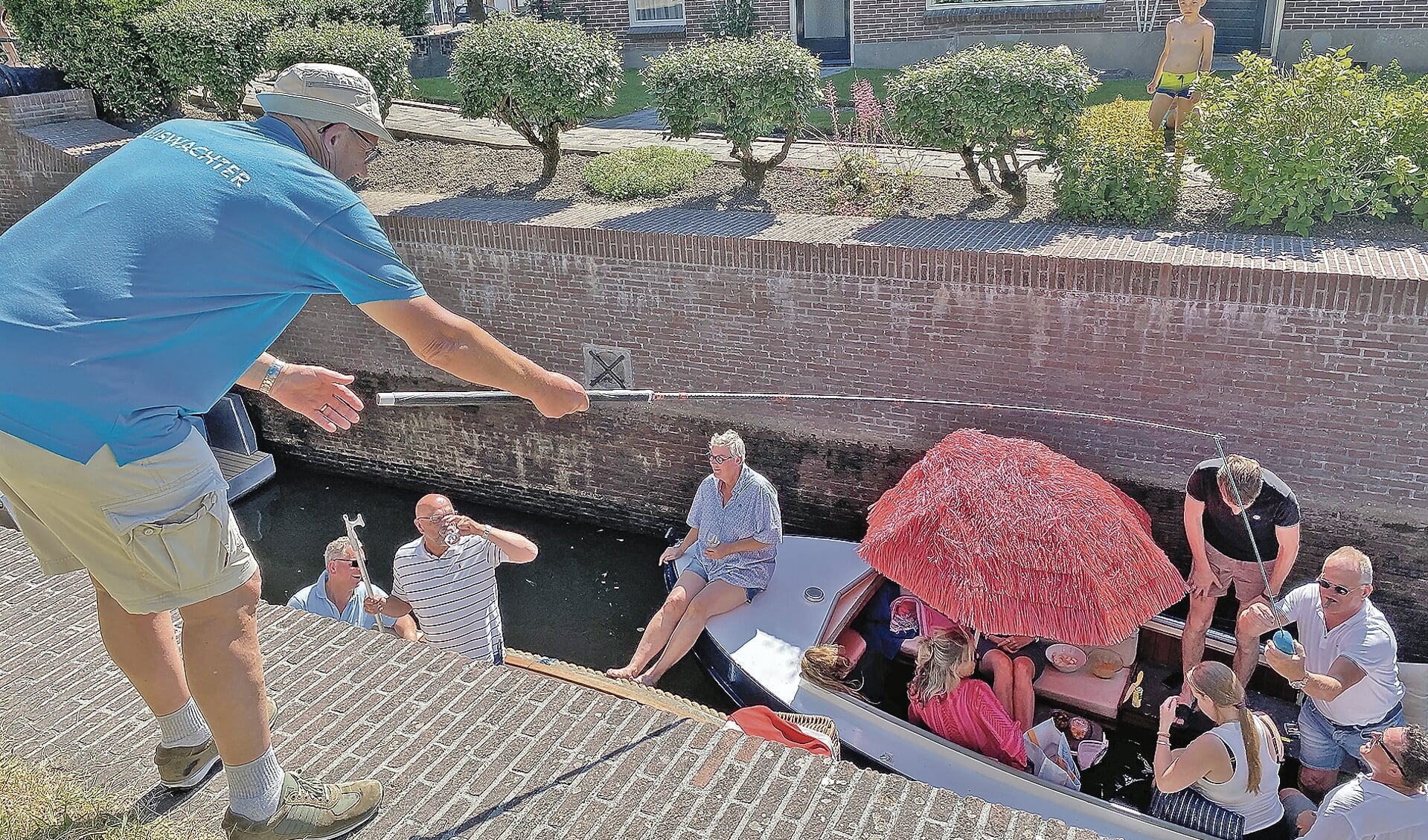 Een van de passerende passagiers van een van de vele bootjes stopt geld in het klompje van de sluiswachter.