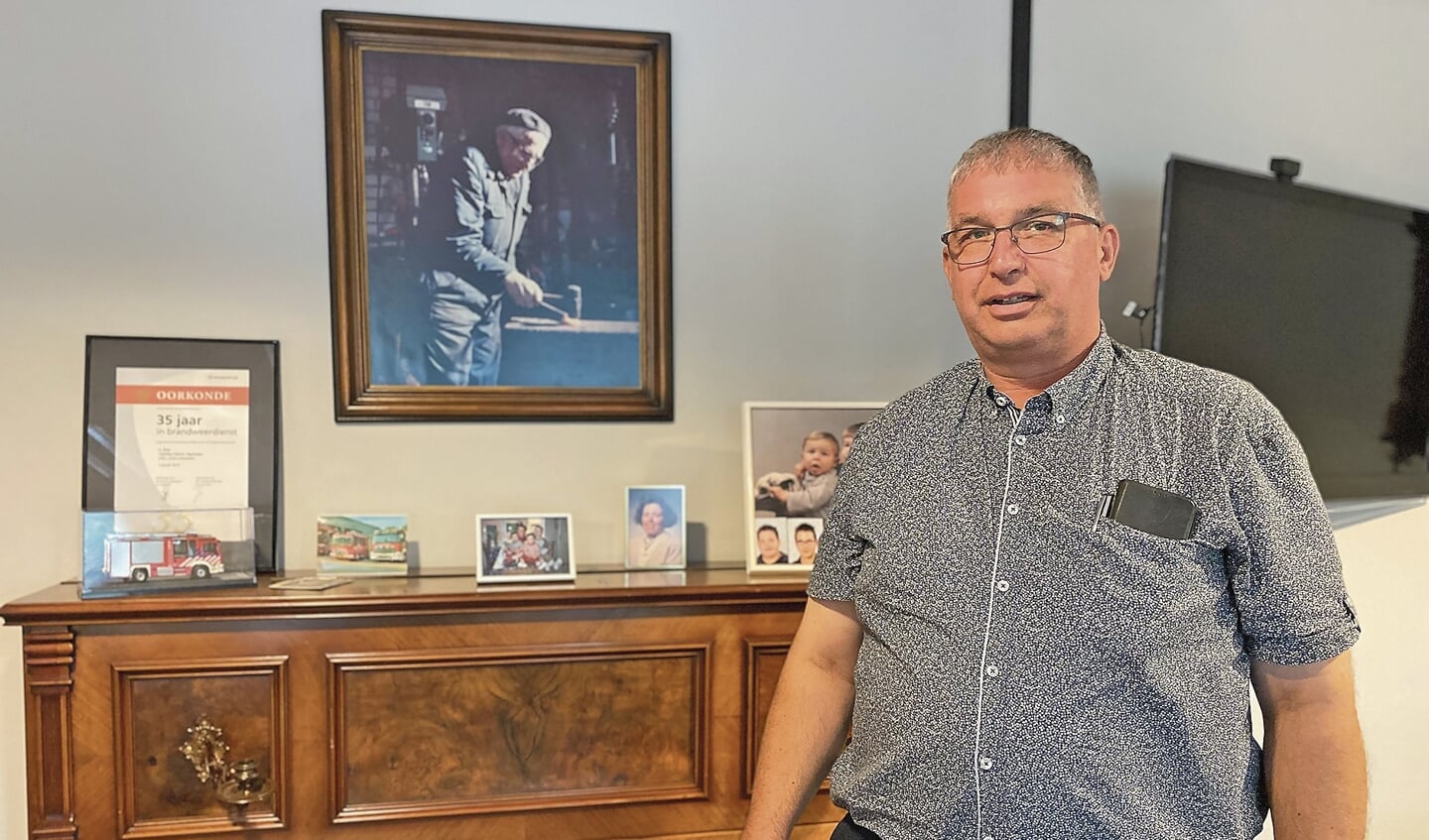 Arie Belo in zijn kantoor met op de achtergrond een foto van zijn vader aan het werk