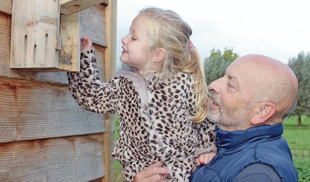 Opa Han Buijze en kleindochter Ninemaken de vogelhuisjes weer in orde.