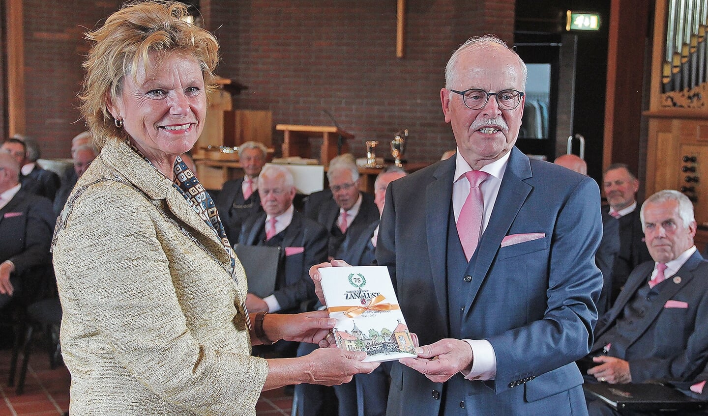 Burgemeester Petra van Hartskamp-De Jong neemt het eerste exemplaarvan het jubileumboekin ontvangst van voorzitter Johan de Jong.