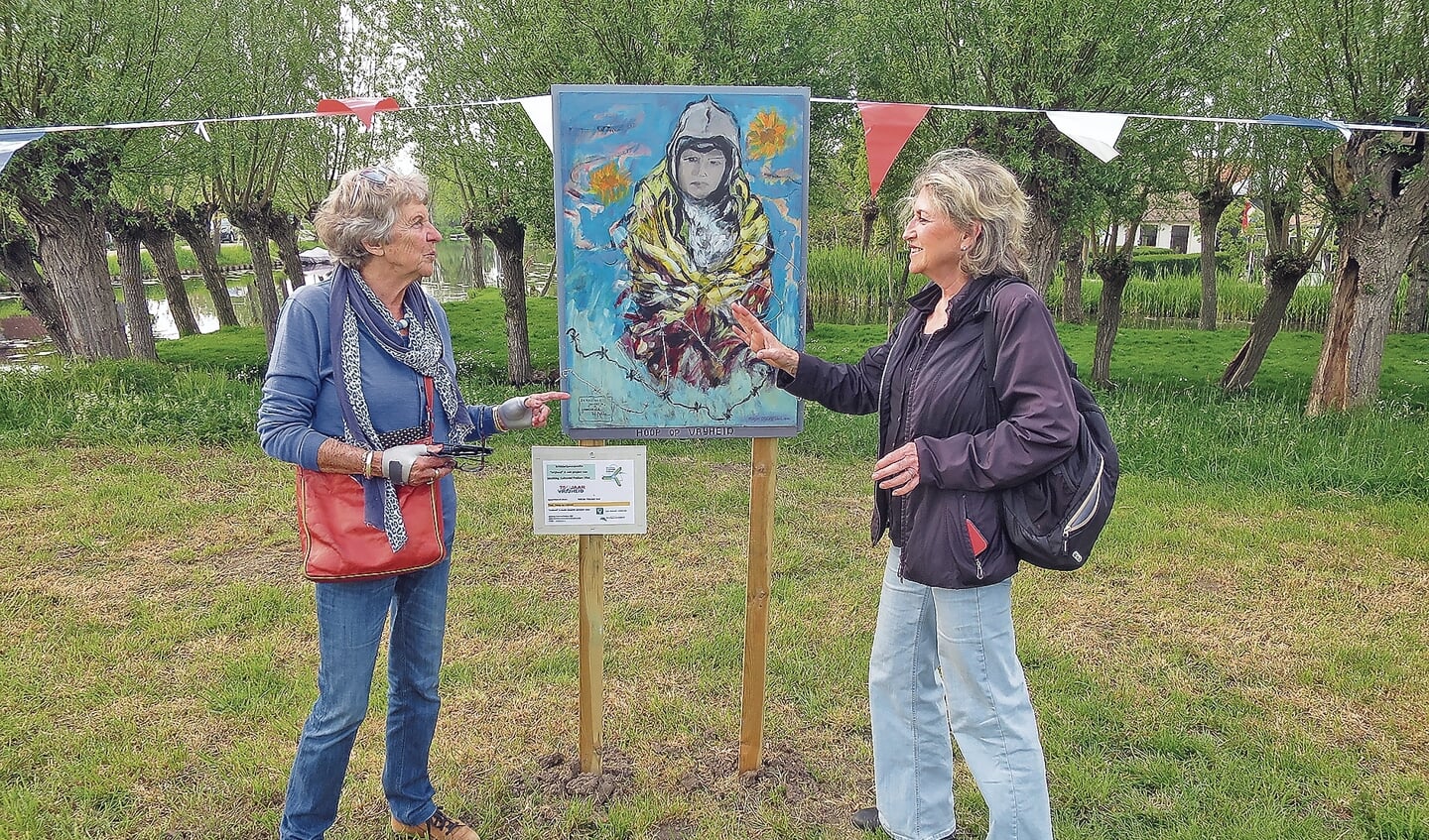Marjan Dijkveld Stol (links) geeft Emmy van Vliet uitleg over haar schilderij 'Hoop op Vrijheid'.